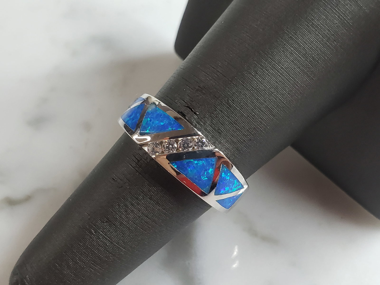 Womens Estate Sterling Silver Modernist Blue Opal Ring: A WOMENS ESTATE STERLING SILVER MODERNIST BLUE OPAL COLORED RING. THE RING IS A SIZE 6.75 AND WEIGHS 4.9g. WIDTH OF RING MEASURES 1/4". NOT SURE IF STONE IS NATURAL OR MAN MADE. THE RING MAKES A BEAUT