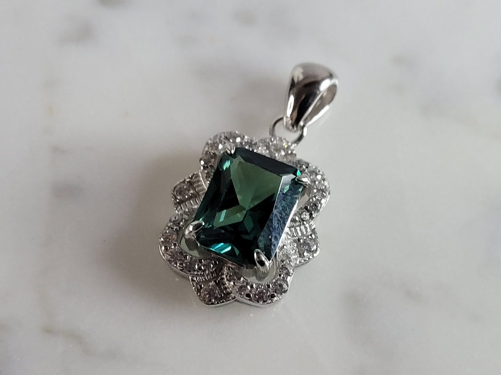 Womens Estate Sterling Silver Modernist CZ Pendant: A WOMENS ESTATE STERLING SILVER MODERNIST CZ PENDANT WITH AN EMERALD COLORED STONE. PENDANT WEIGHS 2.7g AND MEASURES 5/8" LONG BY 1/2" WIDE. MAKES A GREAT GIFT FOR THAT SOMEONE SPECIAL. ANY QUESTIONS,