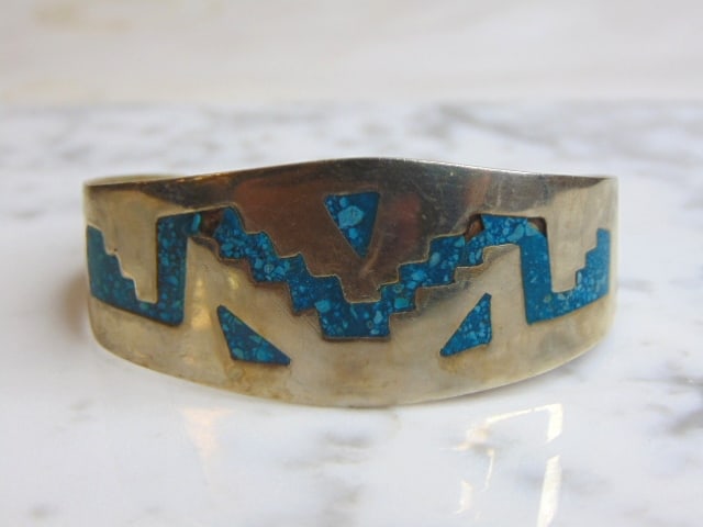 Womens Vintage Estate Southwestern Design Cuff Bracelet w/ Turquoise: A WOMENS VINTAGE ESTATE ALPACCA CUFF BRACELET WITH TURQUOISE INLAY. THE BRACELET WEIGHS 19.8g AND HAS AN INNER CIRCUMFERENCE OF 6 1/2" AND MEASURES 1" WIDE. THE CONDITION IS GOOD BUT AS YOU CAN SEE SO
