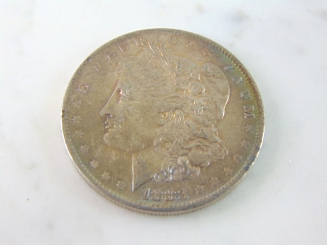 COLLECTIBLE 1883-O MORGAN SILVER DOLLAR W/ TONING: AN 1883-O MORGAN SILVER DOLLAR WITH SLIGHT TONING ALONG THE EDGE WITH A LITTLE MORE ON THE BACK. BUYING AS IS.