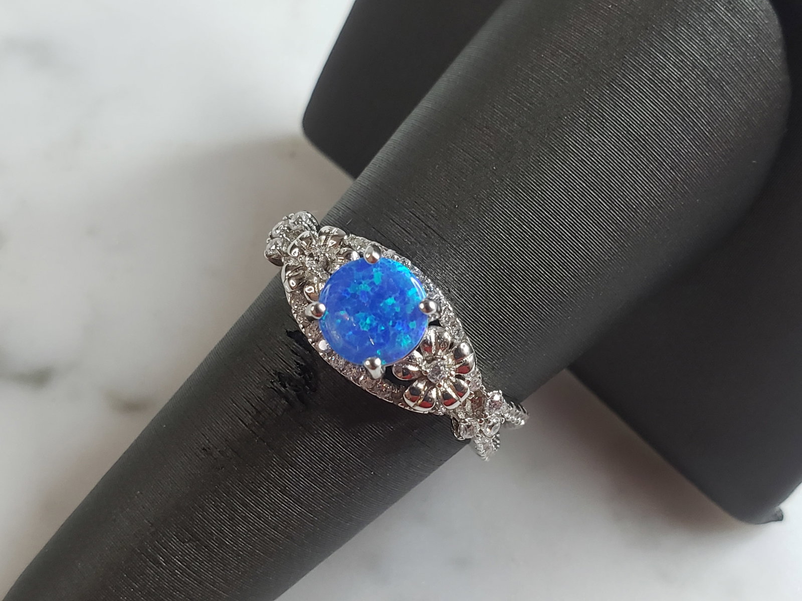 Womens Estate Sterling Silver Modernist Blue Opal Floral Ring: A WOMENS ESTATE STERLING SILVER MODERNIST OPAL COLORED FLORAL RING. THE RING IS A SIZE 8.0 AND WEIGHS 3.2g. WIDTH OF RING MEASURES 3/8". NOT SURE IF STONE IS NATURAL OR MAN MADE. THE RING MAKES A BEAU