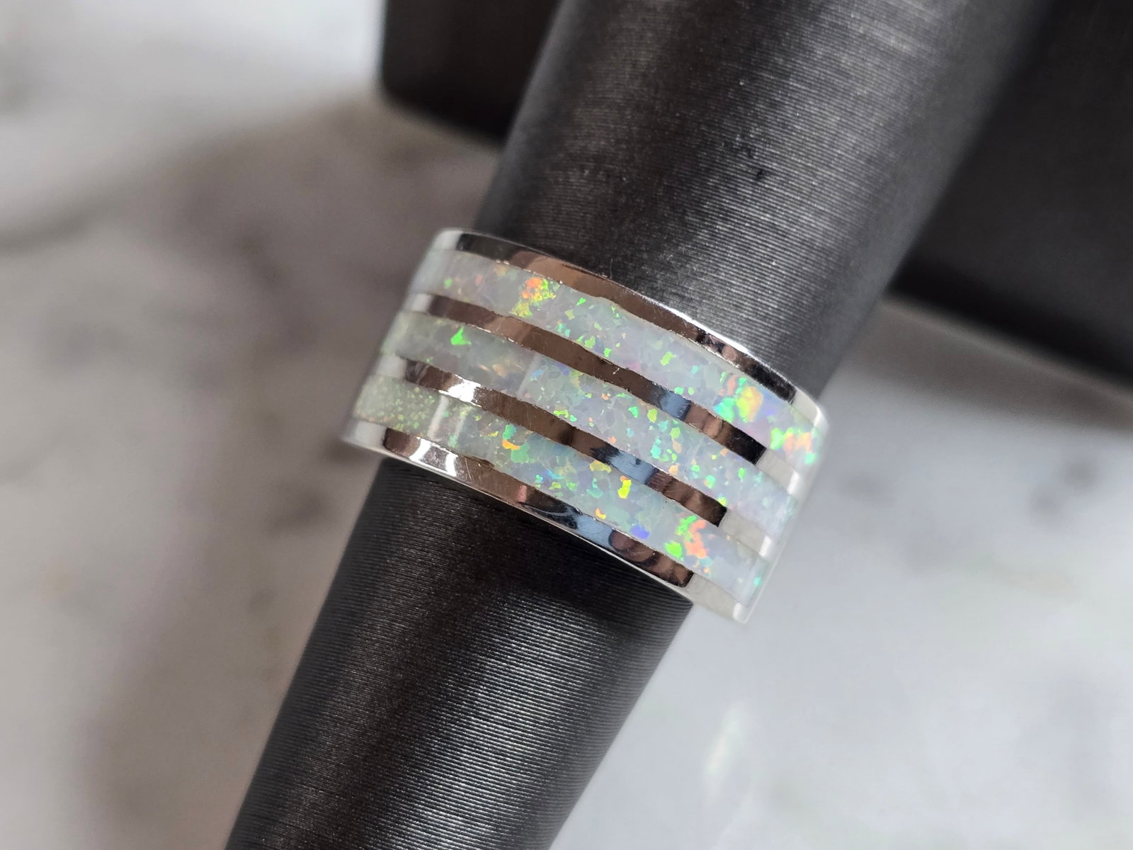 Womens Estate Sterling Silver Modernist Opal Ring: A WOMENS ESTATE STERLING SILVER MODERNIST OPAL COLORED RING. THE RING IS A SIZE 6.25, AND WEIGHS 6.7g. WIDTH OF RING MEASURES 3/8". NOT SURE IF STONE IS NATURAL OR MAN MADE. THE RING MAKES A BEAUTIFUL