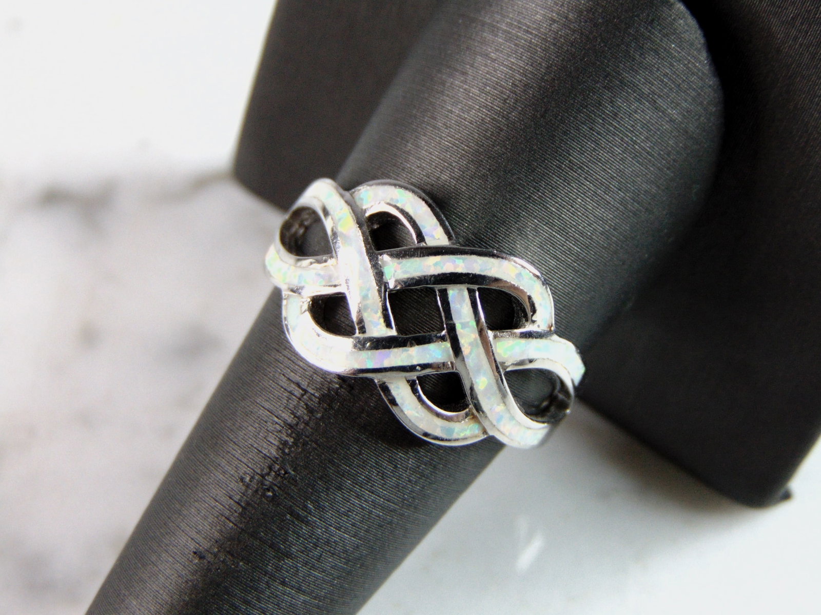 Womens Estate Sterling Silver Eternity Knot Opal Ring: A WOMENS ESTATE STERLING SILVER ETERNITY KNOT OPAL RING. THE RING IS A SIZE 5.0 AND WEIGHS 5.2g. FACE OF RING MEASURES 1/2" WIDE. THE RING MAKES A BEAUTIFUL GIFT FOR THAT SOMEONE SPECIAL. ANY OTHER QU
