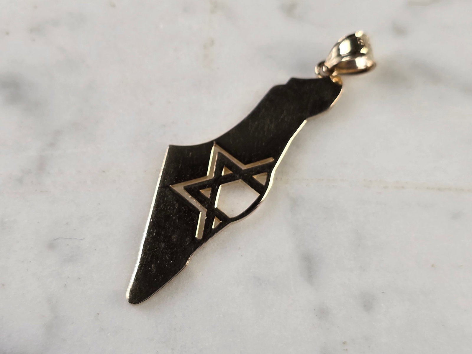 14K Yellow Gold Jewish Judaica Star of David Israel Pendant: A 14K YELLOW GOLD JUDAICA STAR OF DAVID PENDANT IN THE SHAPE OF ISRAEL. THE PENDANT WEIGHS 3.4g AND MEASURES 1 3/4" LONG BY 1/2" WIDE. PENDANT IS MARKED ON THE BALE. MAKES A GREAT GIFT FOR THAT SOMEON