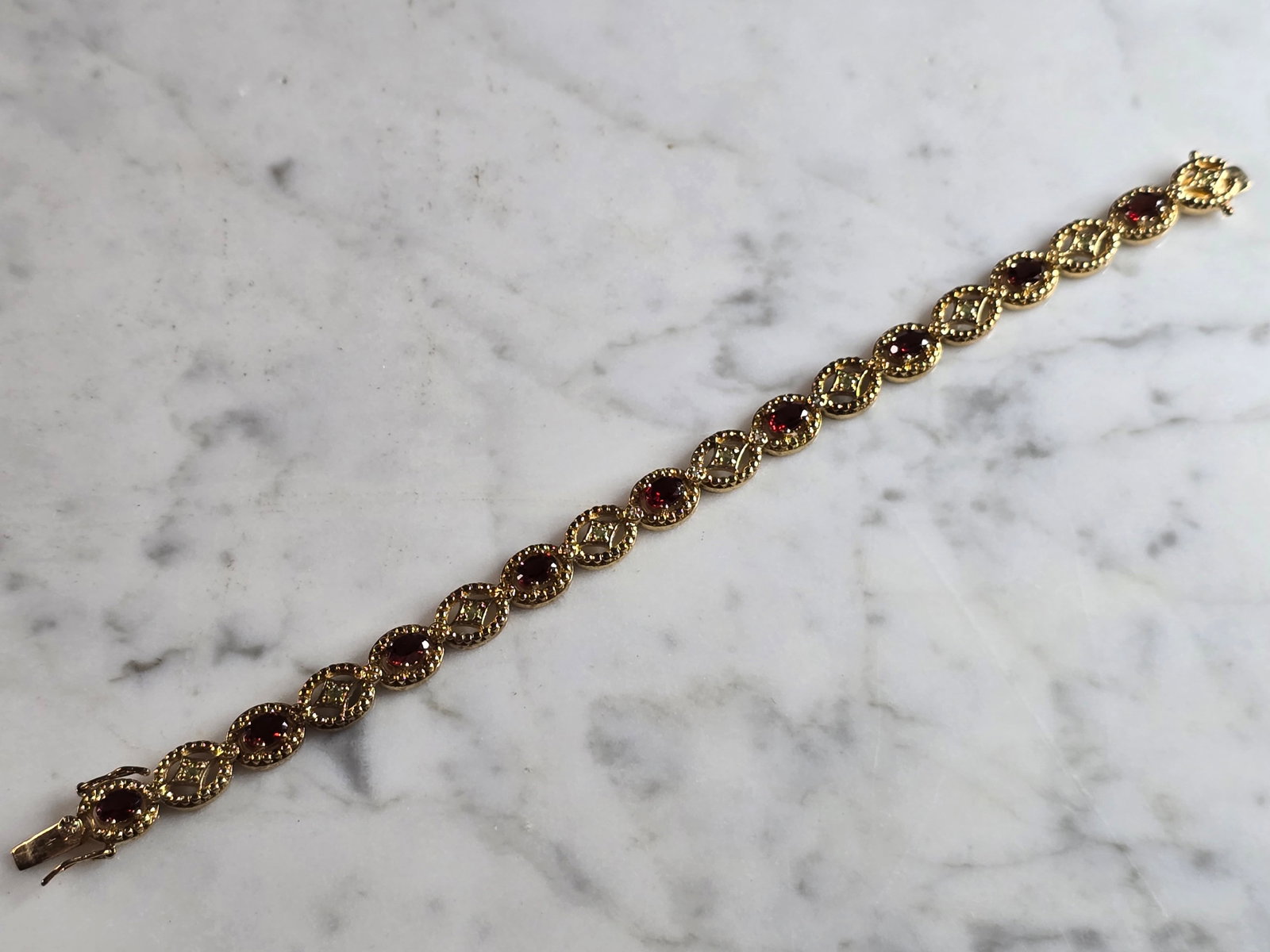 Womens Vintage Estate Sterling Silver Gold Tone Bracelet: A WOMENS VINTAGE ESTATE STERLING SILVER GOLD TONE BRACELET WITH RUBY AND PERIDOT COLORED STONES. BRACELET IS ABOUT 7 3/8" LONG BY 1/4" WIDE AND WEIGHS 18.7g. NOT SURE IF STONES ARE NATURAL OR MAN