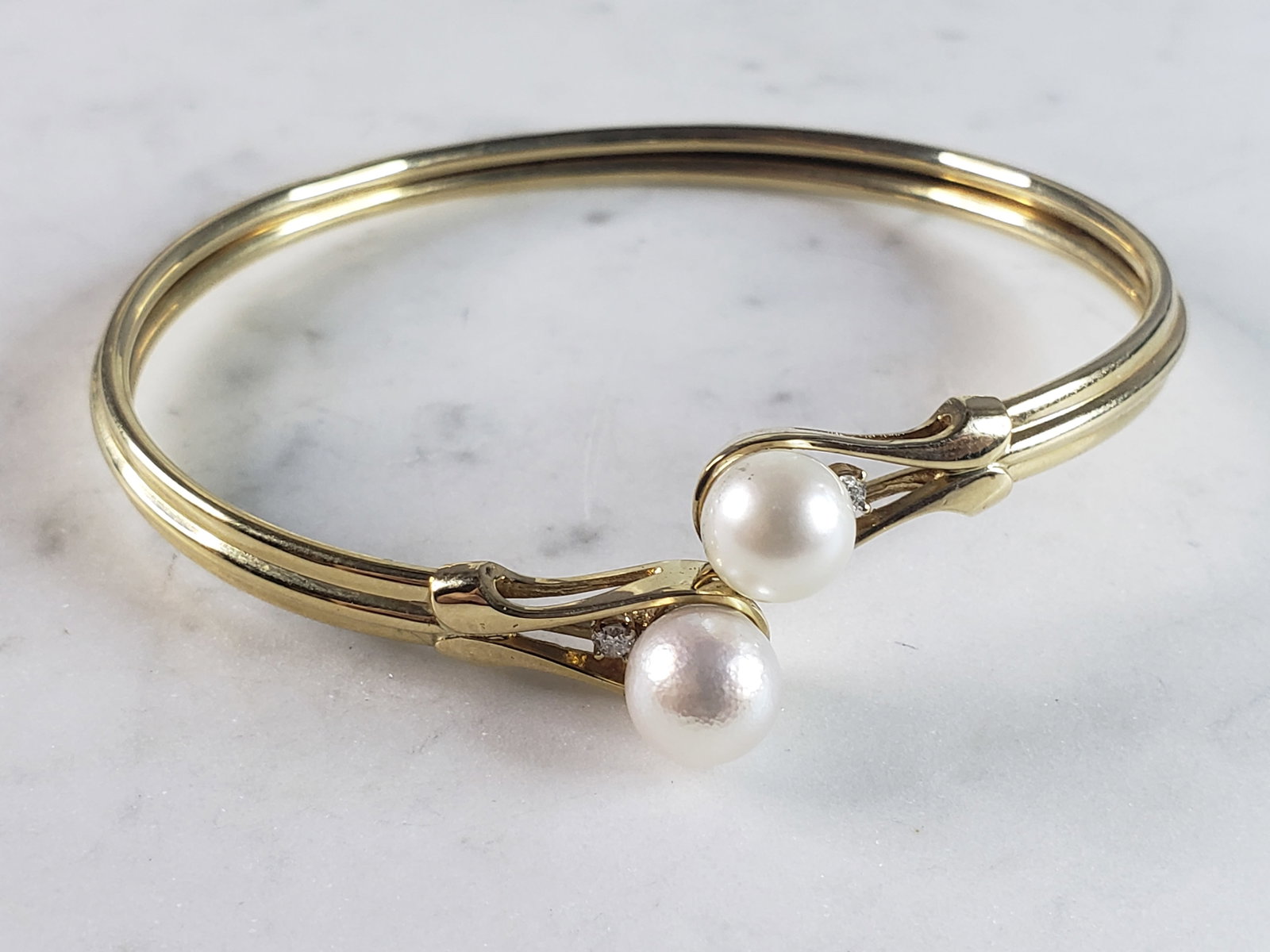 Womens Vintage Estate 14k Gold Pearl & Diamond Bangle Bracelet: A WONDERFUL WOMENS 14k GOLD PEARL & DIAMOND BANGLE BRACELET THAT WEIGHS 12.9g AND MEASURES ABOUT 8 1/2" IN CIRCUMFERENCE. BRACELET IS MARKED 14K. THERE ARE ABOUT .14cts OF DIAMONDS. NOT SURE IF THE PE