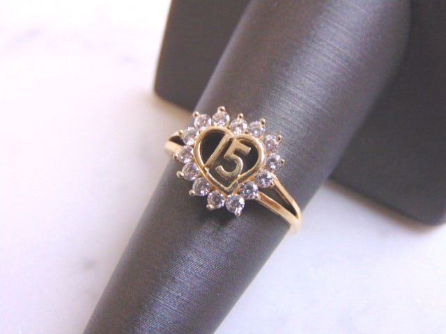 Womens Vintage Estate 14k Gold La Quinceanera Ring: A WOMENS VINTAGE ESTATE 14K GOLD, LA QUINCEANERA HEART RING. THE RING IS A SIZE 6.75 AND WEIGHS 2.4g. THE STONES ARE EITHER CUBIC ZIRCONIA OR CRYSTALS. THIS IS A LOVELY GIFT FOR A YOUNG WOMAN TURNING 