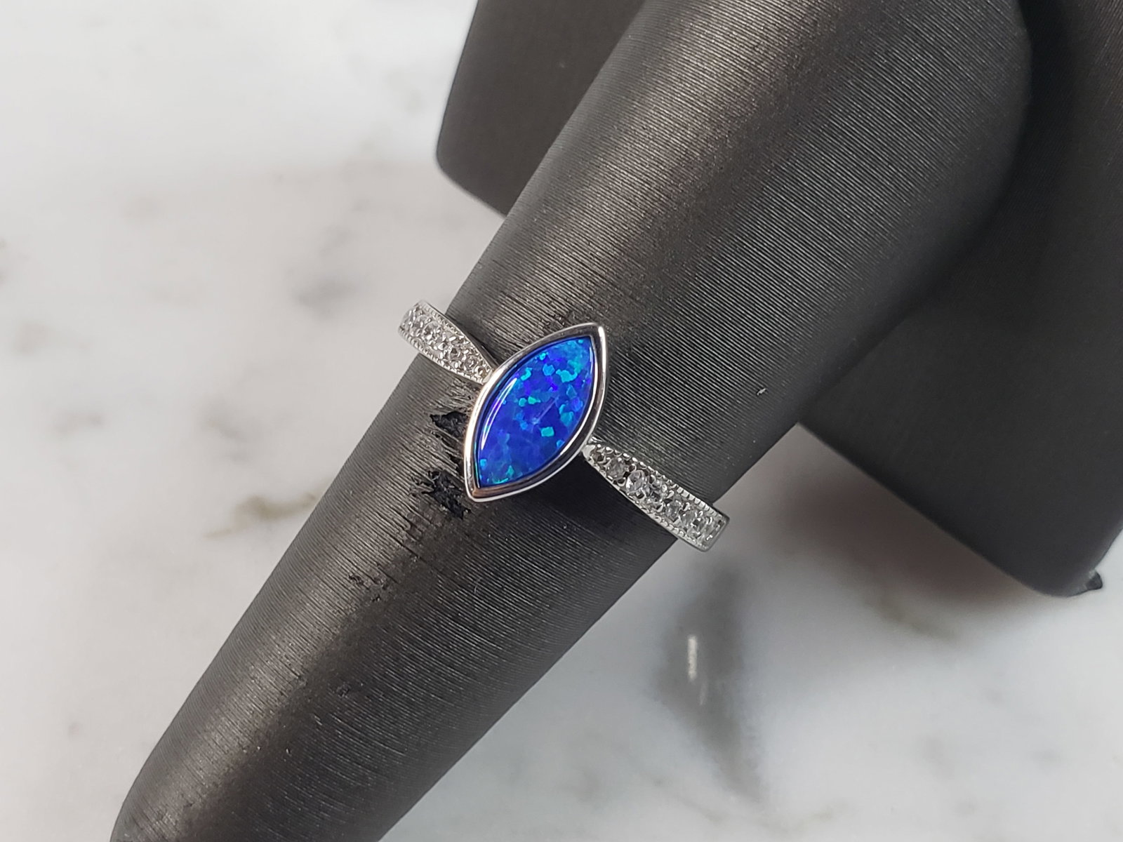 Womens Estate Sterling Silver Modernist Blue Opal & CZ Ring: A WOMENS ESTATE STERLING SILVER MODERNIST BLUE OPAL COLORED RING. THE RING IS A SIZE 7.75 AND WEIGHS 2.5g. WIDTH OF RING MEASURES 3/8". NOT SURE IF STONE IS NATURAL OR MAN MADE. THE RING MAKES A BEAUT