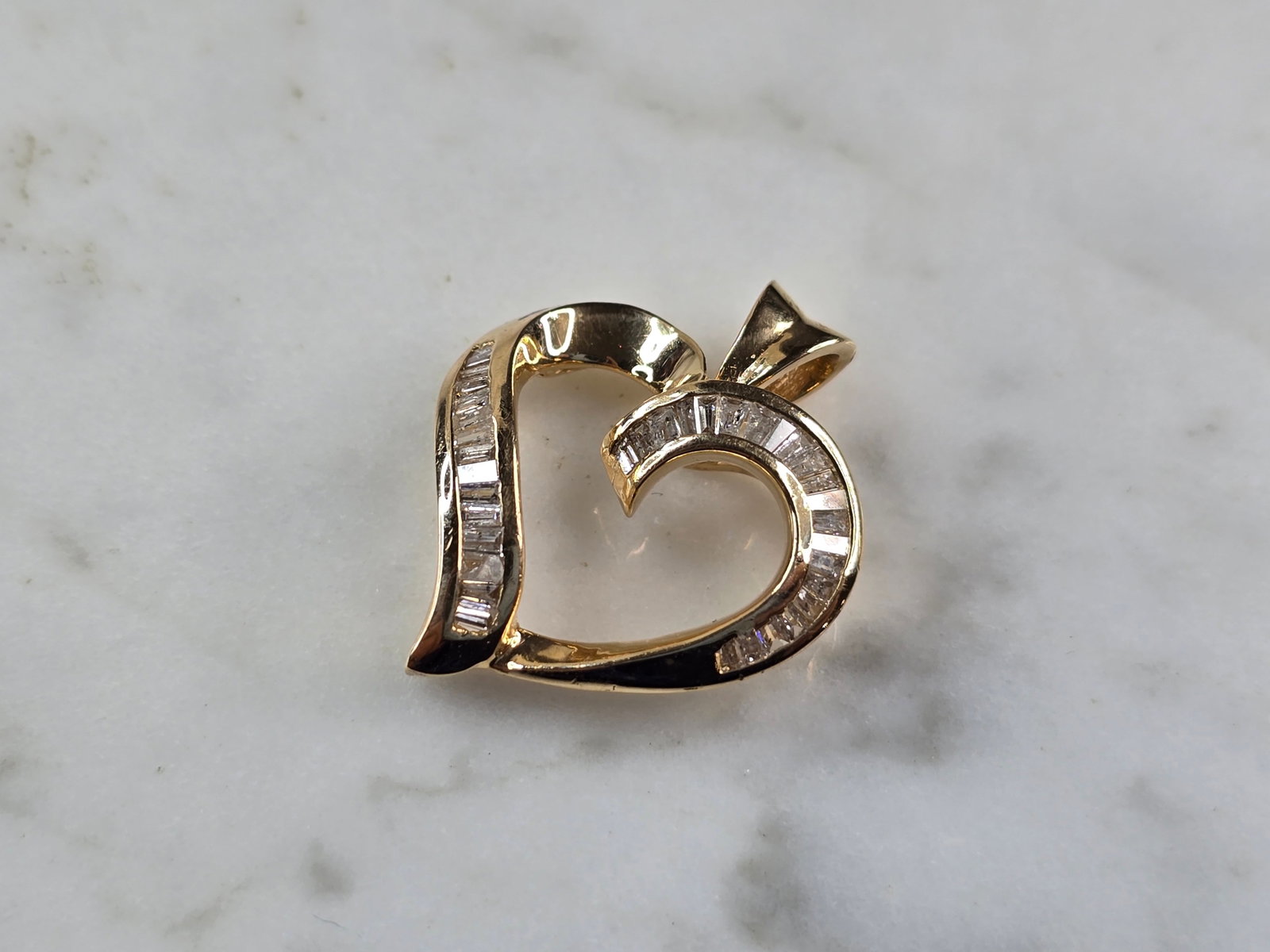 Womens Vintage Estate 14K Yellow Gold Diamond Heart Pendant: A WOMENS VINTAGE ESTATE 14K YELLOW GOLD DIAMOND HEART PENDANT. THE TOTAL WEIGHT IS 3.8g. THE PENDANT MEASURES 7/8" LONG BY 3/4" WIDE. THERE ARE 36 BAGUETTE DIAMONDS IN THIS PENDANT. MAKES A GREAT GIFT