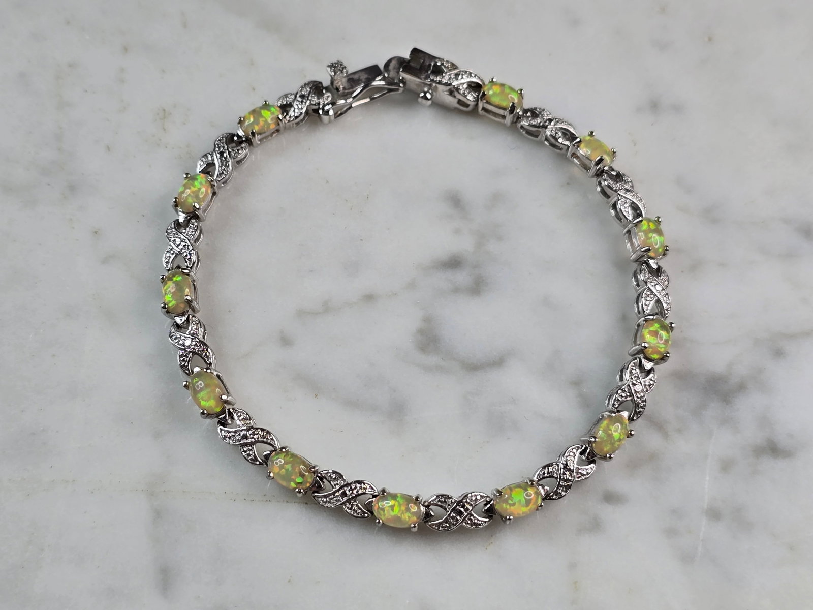 Womens Vintage Estate Sterling Silver Opal Tennis Bracelet: A WOMENS VINTAGE ESTATE STERLING SILVER OPAL TENNIS BRACELET. THE BRACELET MEASURES 7 1/4" LONG BY 1/8" WIDE, AND WEIGHS 9.4g. NOT SURE IF STONES ARE NATURAL OR MAN MADE. WOULD MAKE A GREAT GIFT FOR T