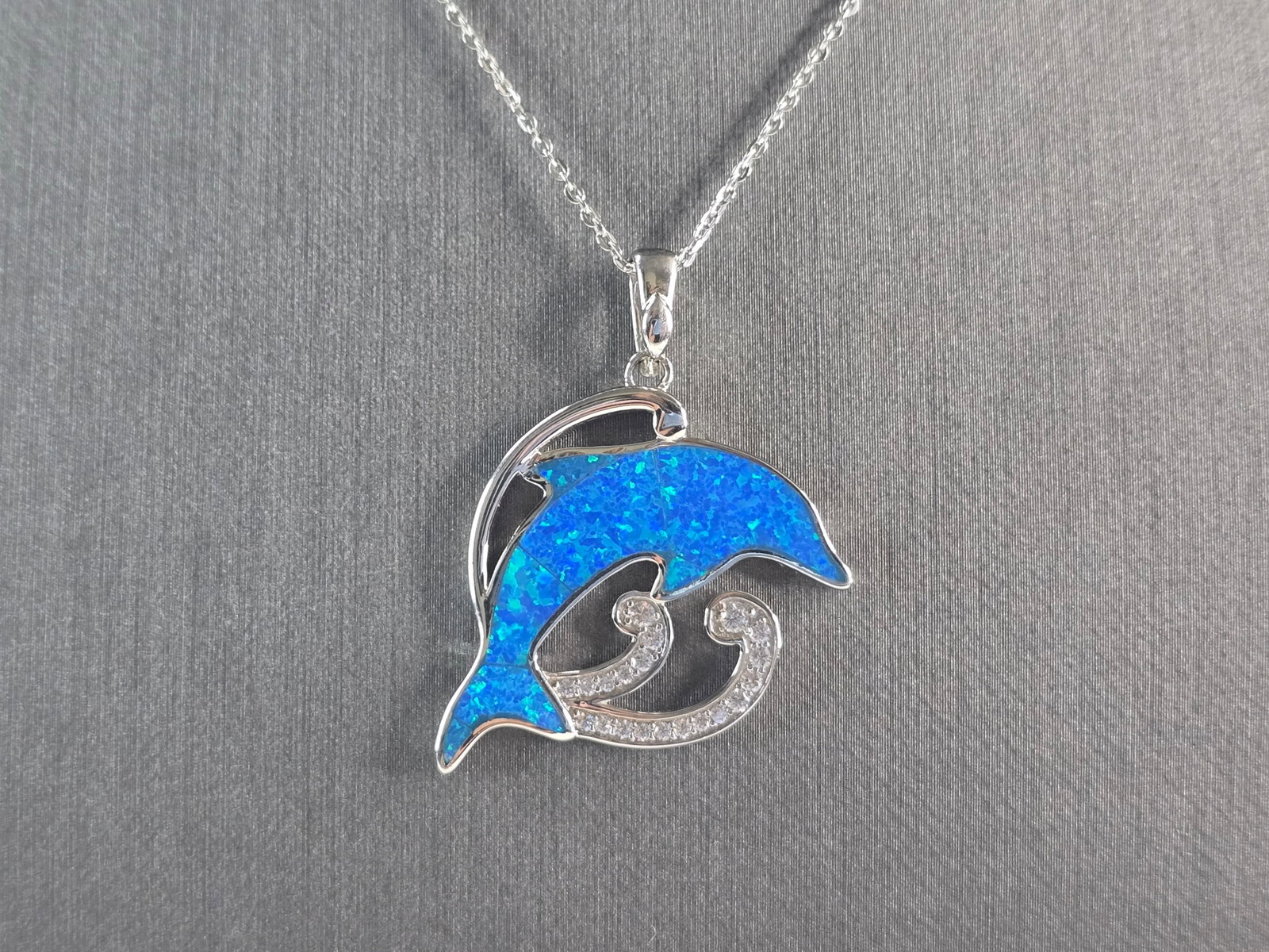 Womens Sterling Silver Blue Opal Dolphin Pendant Necklace: A WOMENS STERLING SILVER BLUE OPAL DOLPHIN PENDANT WITH NECKLACE. THE PENDANT WITH NECKLACE WEIGHS 6.7g. PENDANT MEASURES 1 3/8" LONG BY 1" WIDE, AND THE NECKLACE MEASURES 18" LONG, ADJUSTABLE TO 16".