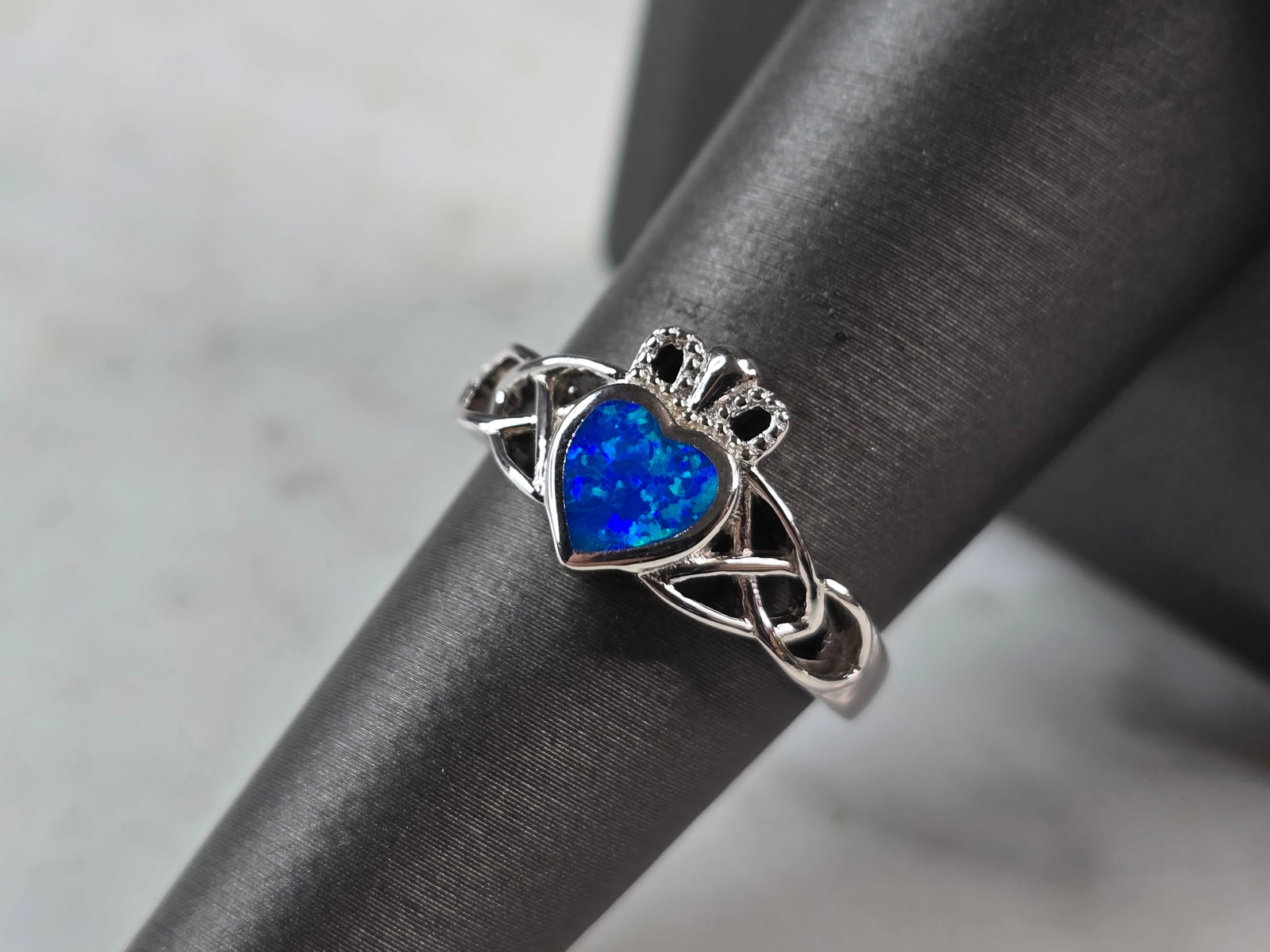 Womens Sterling Silver Irish Claddagh Blue Opal Heart Ring: A WOMENS STERLING SILVER IRISH CLADDAGH BLUE OPAL COLORED HEART RING. THE RING IS A SIZE 7.0, AND WEIGHS 3.3g. THE WIDTH OF RING MEASURES 3/8". NOT SURE IF INLAY IS NATURAL OR MAN MADE. THE RING MAKES