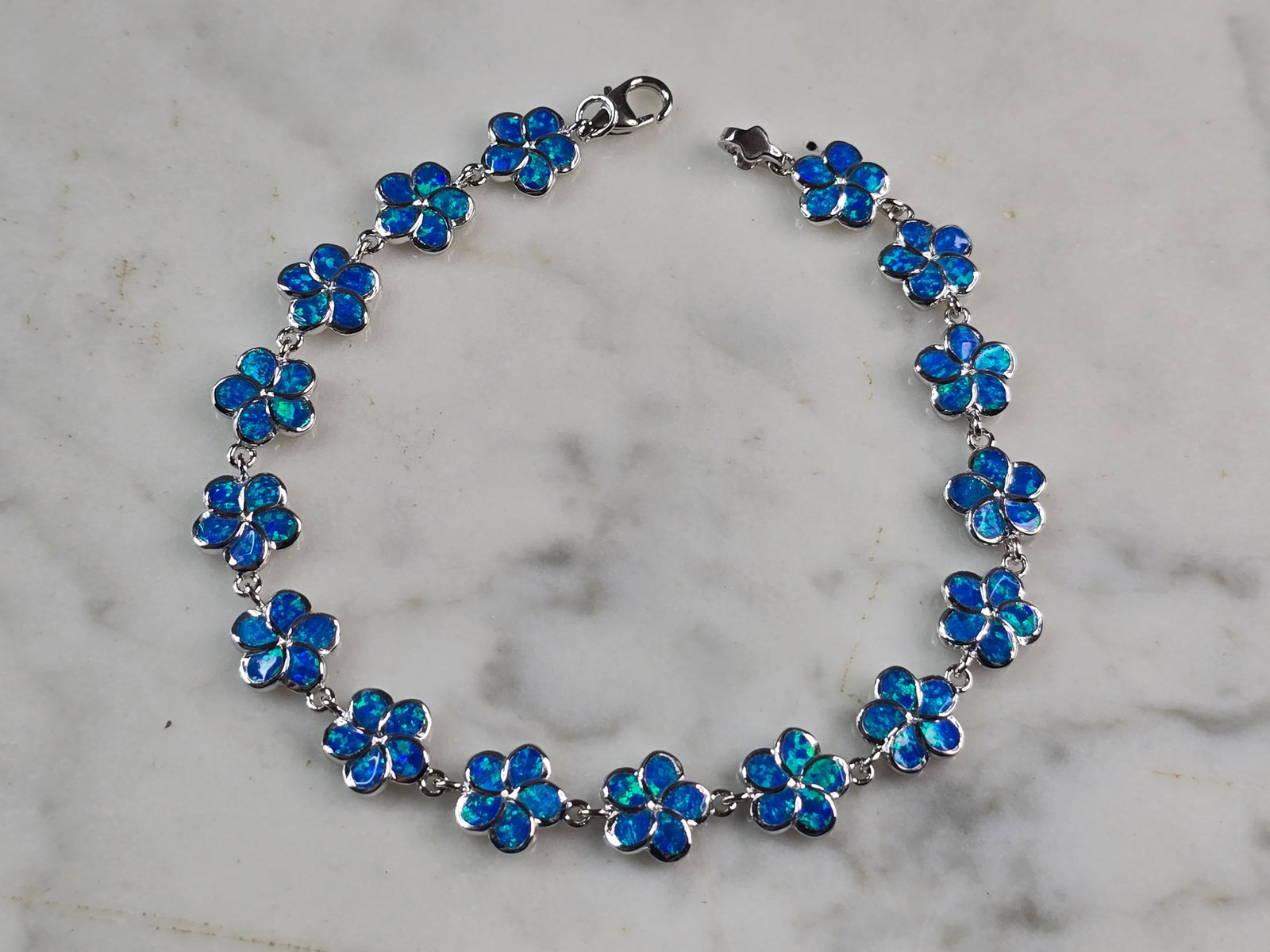 Womens Sterling Silver Blue Opal Floral Bracelet: A WOMENS STERLING SILVER BLUE OPAL COLORED FLORAL BRACELET. THE BRACELET WEIGHS 9.6g AND MEASURES 7 1/2" LONG BY 5/16" WIDE. NOT SURE IF OPAL IS NATURAL OR MAN MADE. ANY QUESTIONS PLEASE DO NOT HESITA