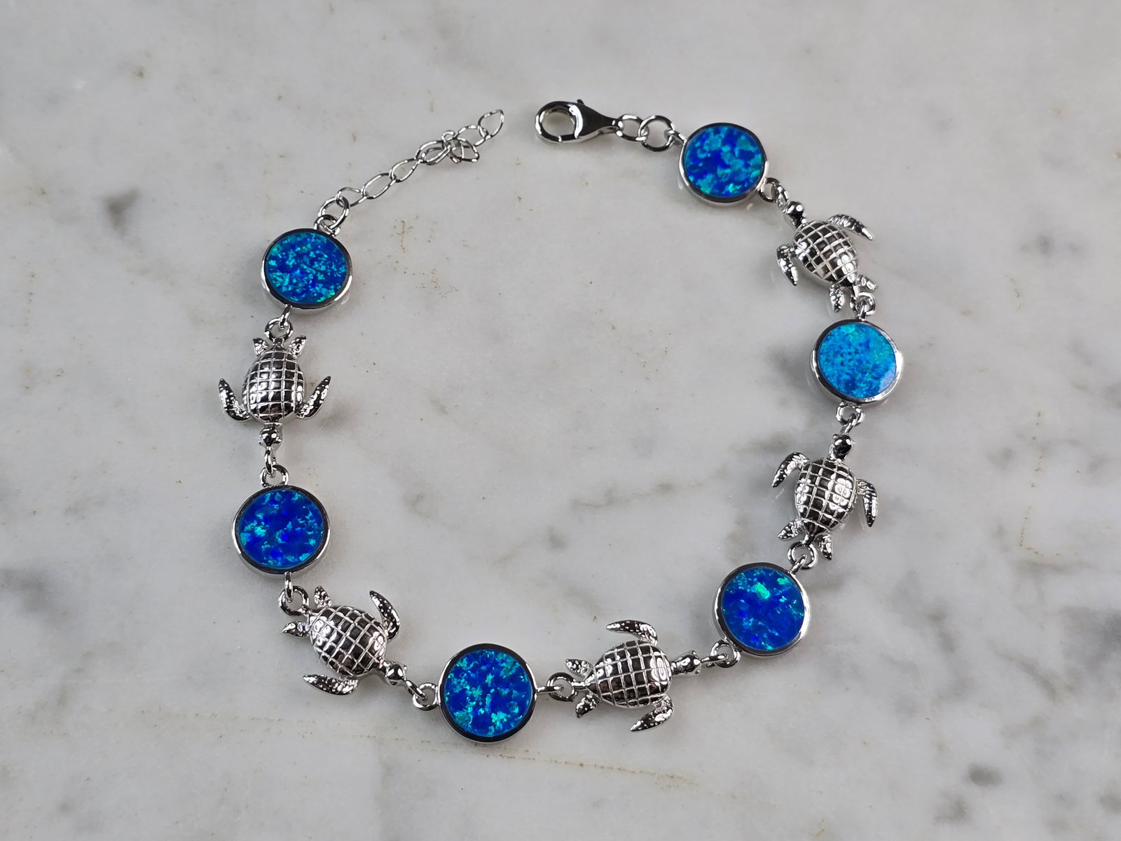 Womens Sterling Silver Blue Opal Sea Turtle Ocean Bracelet: A WOMENS ESTATE STERLING SILVER BLUE OPAL COLORED SEA TURTLE OCEAN BRACELET. THE BRACELET WEIGHS 9.2g AND MEASURES 8" LONG BY 3/8" WIDE. NOT SURE IF OPAL IS NATURAL OR MAN MADE. ANY QUESTIONS PLEASE D