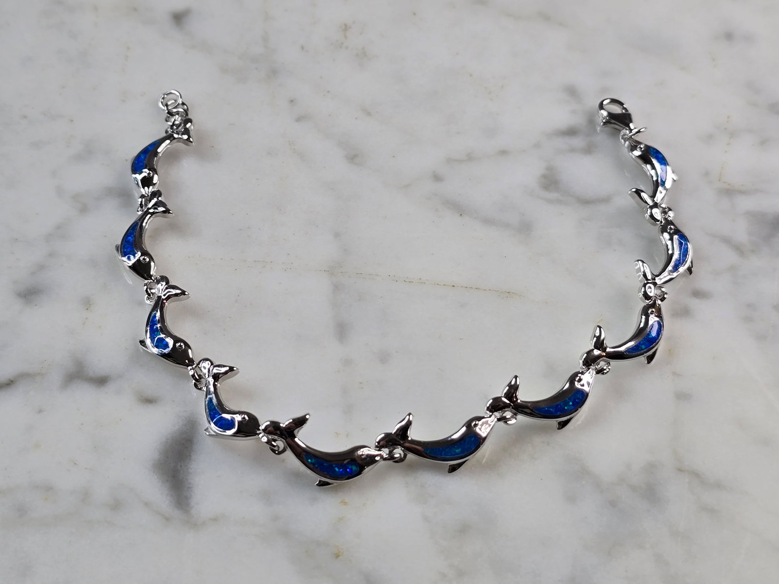 Womens Sterling Silver Blue Opal Dolphin Ocean Bracelet: A WOMENS STERLING SILVER BLUE OPAL COLORED DOLPHIN OCEAN BRACELET. THE BRACELET WEIGHS 10.9g AND MEASURES 7 1/2" LONG BY 3/8" WIDE. NOT SURE IF OPAL IS NATURAL OR MAN MADE. ANY QUESTIONS PLEASE DO NOT