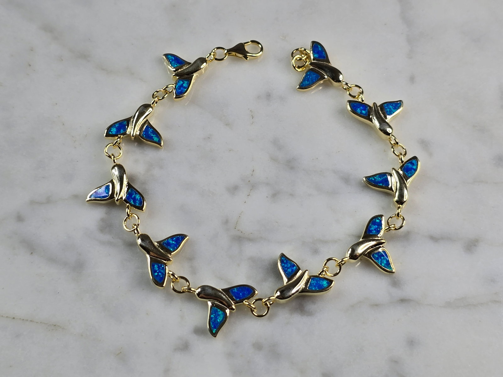 Womens Sterling Silver Gold Tone Blue Opal Whale Tail Ocean Bracelet: A WOMENS STERLING SILVER GOLD TONE BLUE OPAL COLORED WHALE TAIL OCEAN BRACELET. THE BRACELET WEIGHS 11.8g AND MEASURES 7 1/2" LONG BY 1/2" WIDE. NOT SURE IF OPAL IS NATURAL OR MAN MADE. ANY QUESTIONS 