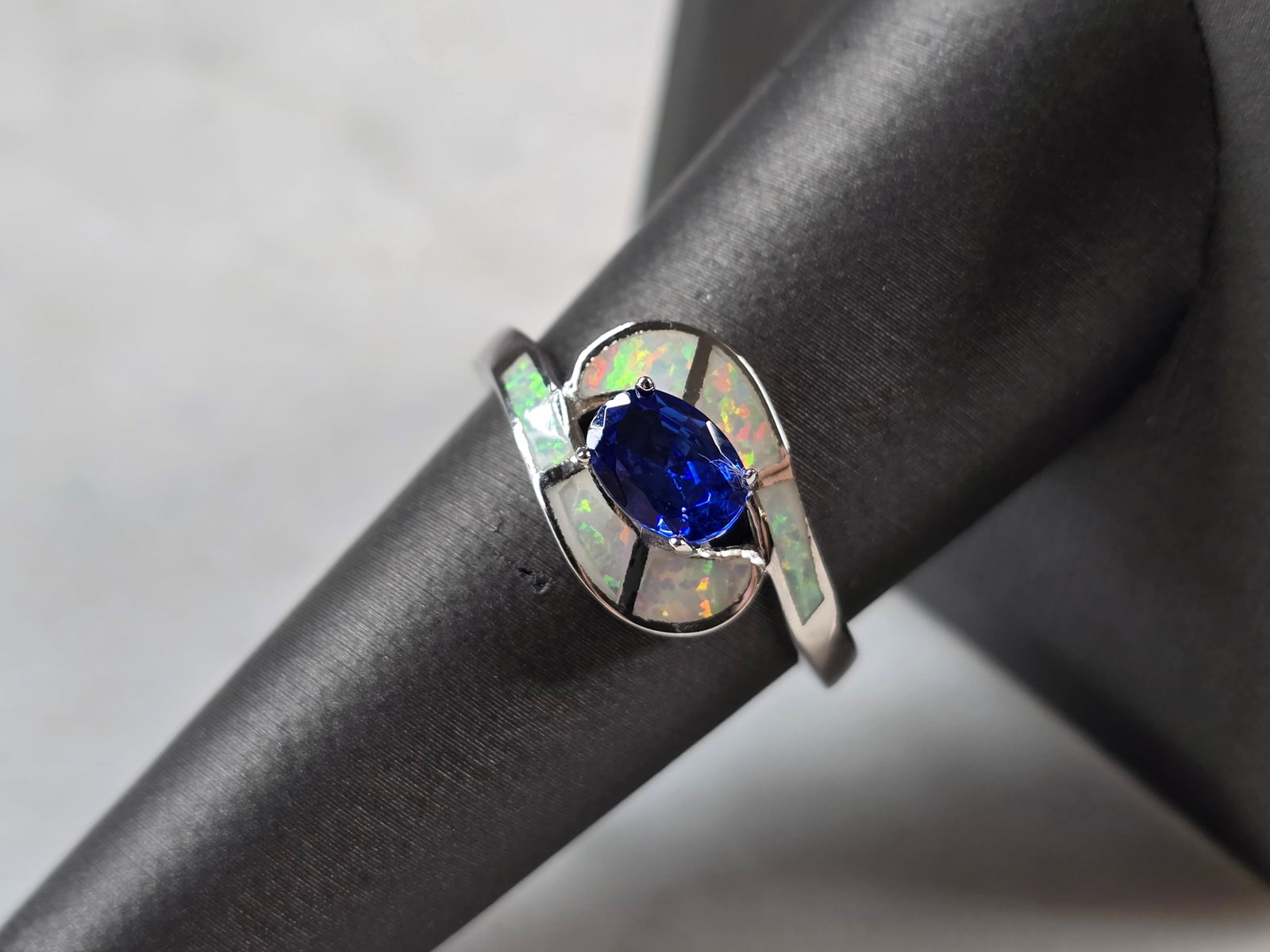 Womens Sterling Silver Opal Tanzanite Modernist Ring: A WOMENS STERLING SILVER OPAL & TANZANITE COLORED MODERNIST RING. THE RING IS A SIZE 8.25, AND WEIGHS 3.3g. WIDTH OF RING MEASURES 3/8". NOT SURE IF STONE IS NATURAL OR MAN MADE. THE RING MAKES A BEAU
