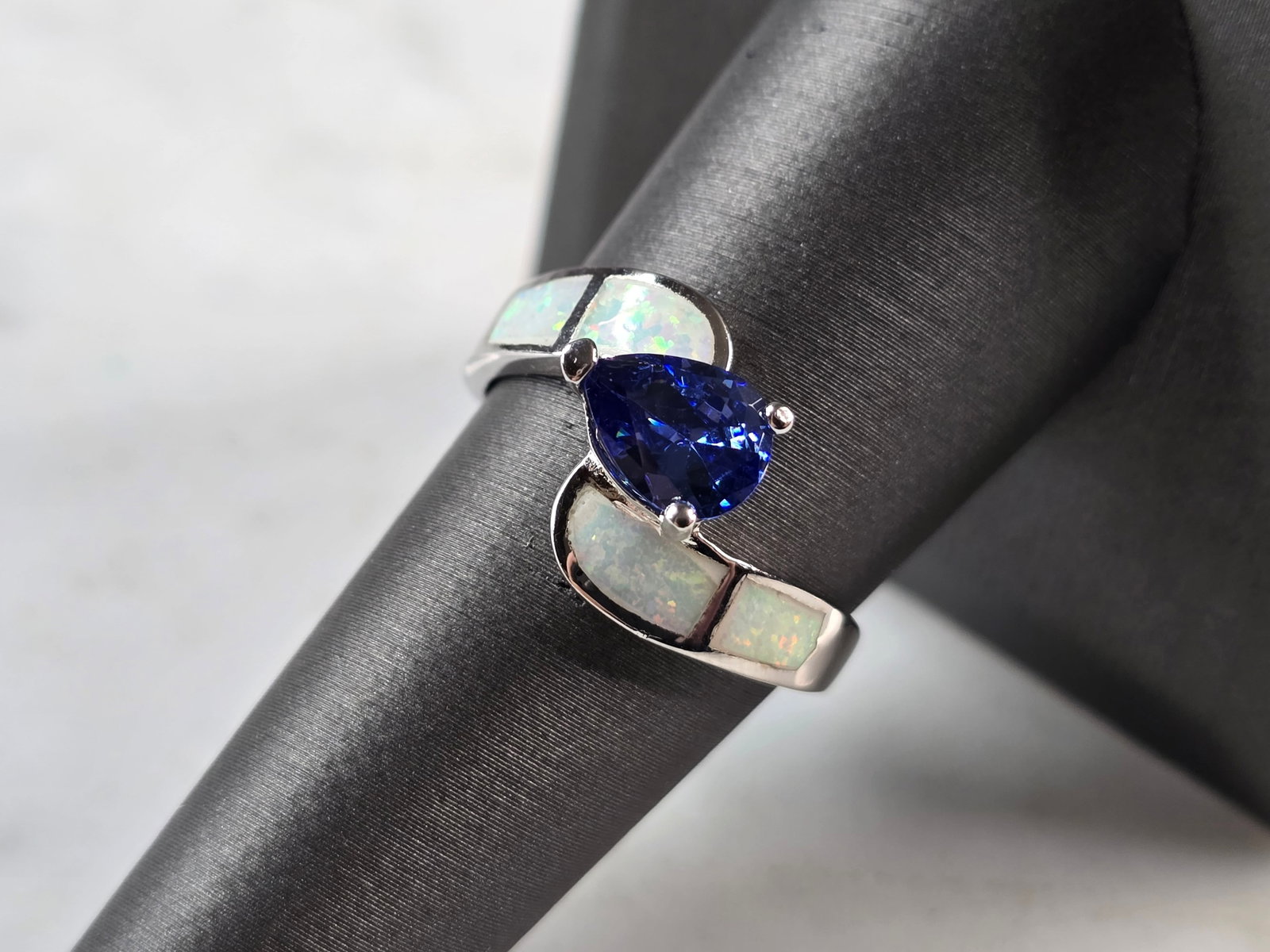 Womens Sterling Silver Opal Tanzanite Modernist Ring: A WOMENS STERLING SILVER OPAL & TANZANITE COLORED MODERNIST RING. THE RING IS A SIZE 8.25, AND WEIGHS 3.8g. WIDTH OF RING MEASURES 1/2". NOT SURE IF STONE IS NATURAL OR MAN MADE. THE RING MAKES A BEAU