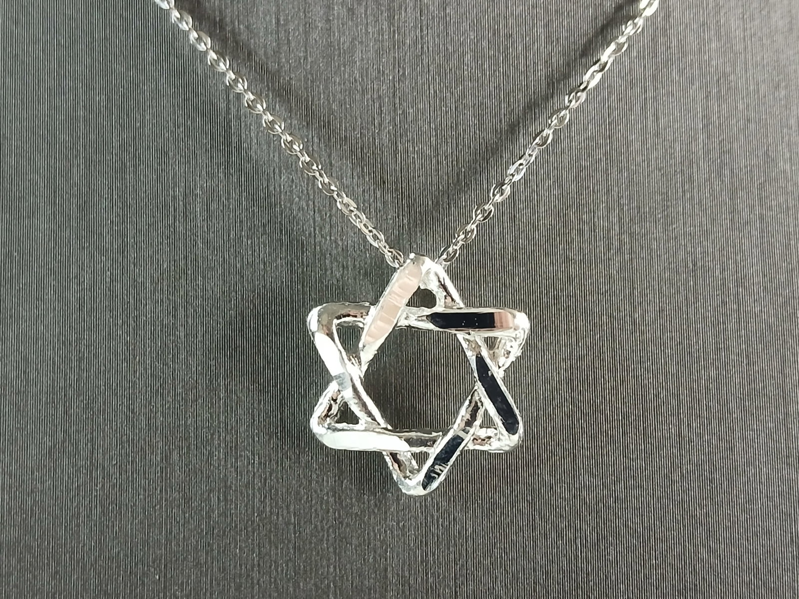 Sterling Silver Star of David Jewish Judaica Pendant Necklace: A STERLING SILVER STAR OF DAVID MODERNIST STYLE PENDANT WITH NECKLACE. PENDANT WITH NECKLACE WEIGHS 3.7g. PENDANT MEASURES 5/8" WIDE BY 5/8" LONG. THE NECKLACE MEASURES 18" LONG, ADJUSTABLE TO 16" LON