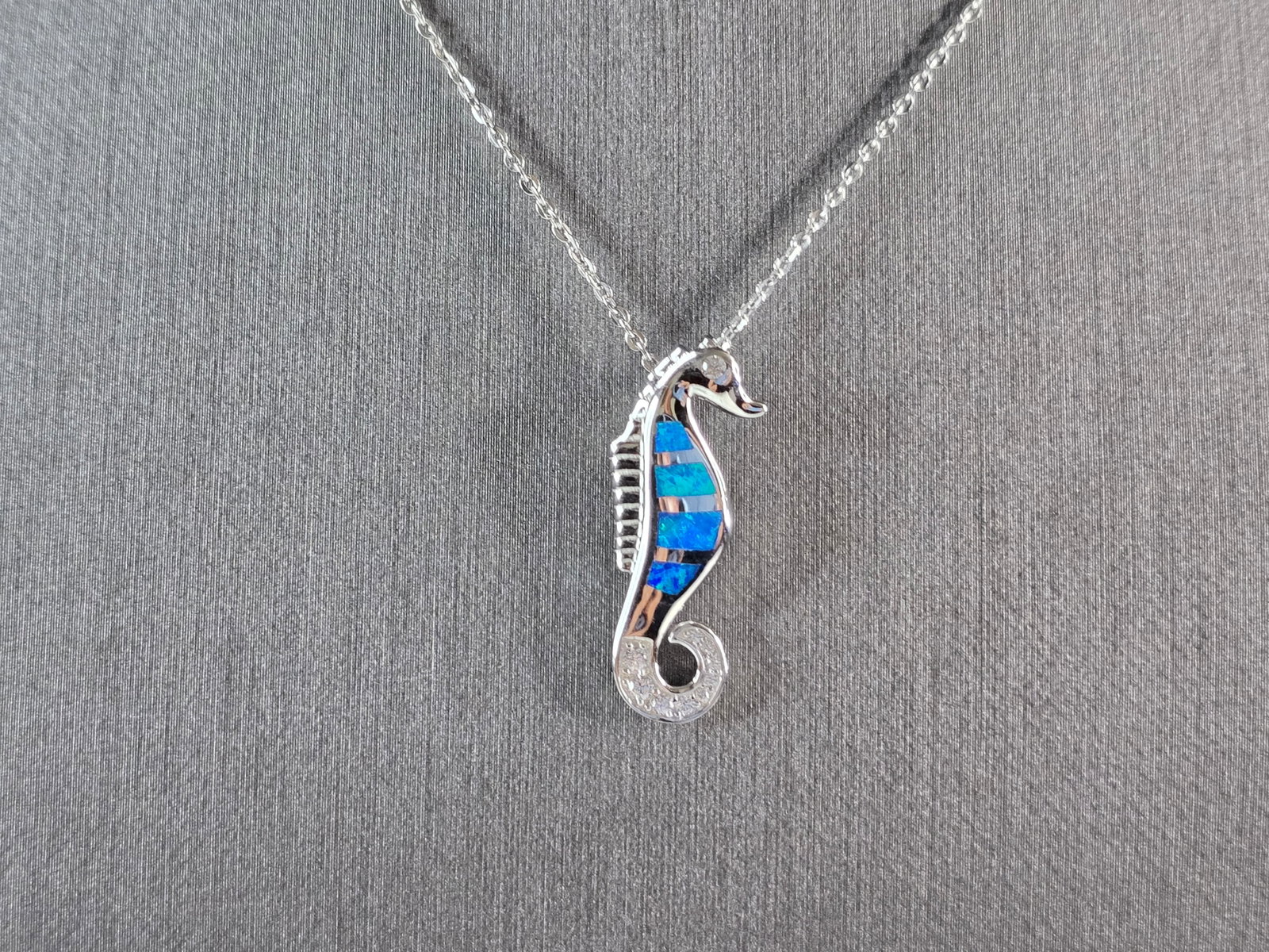 Womens Sterling Silver Blue Opal Seahorse Pendant Necklace: A WOMENS STERLING SILVER BLUE OPAL SEAHORSE PENDANT. THE PENDANT WITH NECKLACE WEIGHS 4.4g. THE PENDANT MEASURES 1" LONG BY 3/8" WIDE. THE NECKLACE MEASURES 18" LONG AND IS ADJUSTABLE TO 16" LONG. NOT