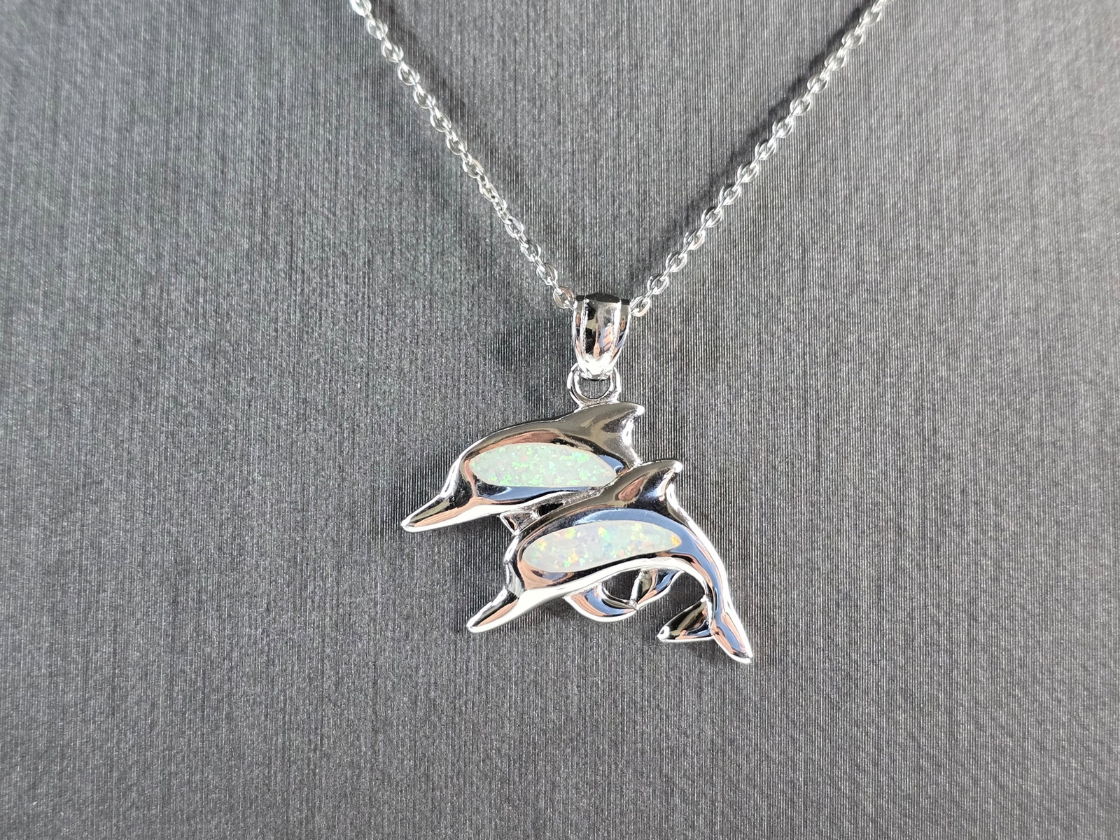 Womens Sterling Silver Opal Dolphin Pendant Necklace: A WOMENS STERLING SILVER OPAL DOLPHIN PENDANT. THE PENDANT WITH NECKLACE WEIGHS 4.7g. THE PENDANT MEASURES 1" LONG BY 1" WIDE, AND THE NECKLACE MEASURES 18" LONG. NOT SURE IF STONES ARE REAL OR MAN MA