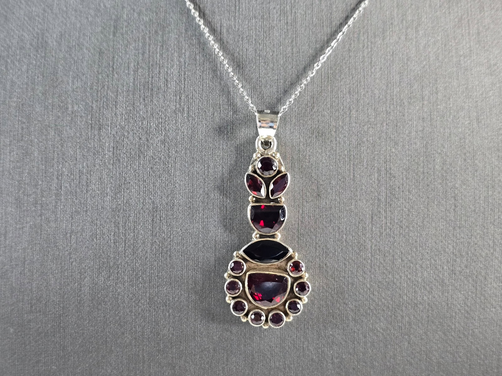 Womens Estate Sterling Silver Garnet Cluster Pendant Necklace: A WOMENS ESTATE STERLING SILVER PENDANT WITH GARNET COLORED STONES. PENDANT WITH NECKLACE WEIGHS 10.1g. THE PENDANT MEASURES 1 3/4" LONG BY 5/8" WIDE, AND THE NECKLACE MEASURES 18" LONG. NOT SURE IF T