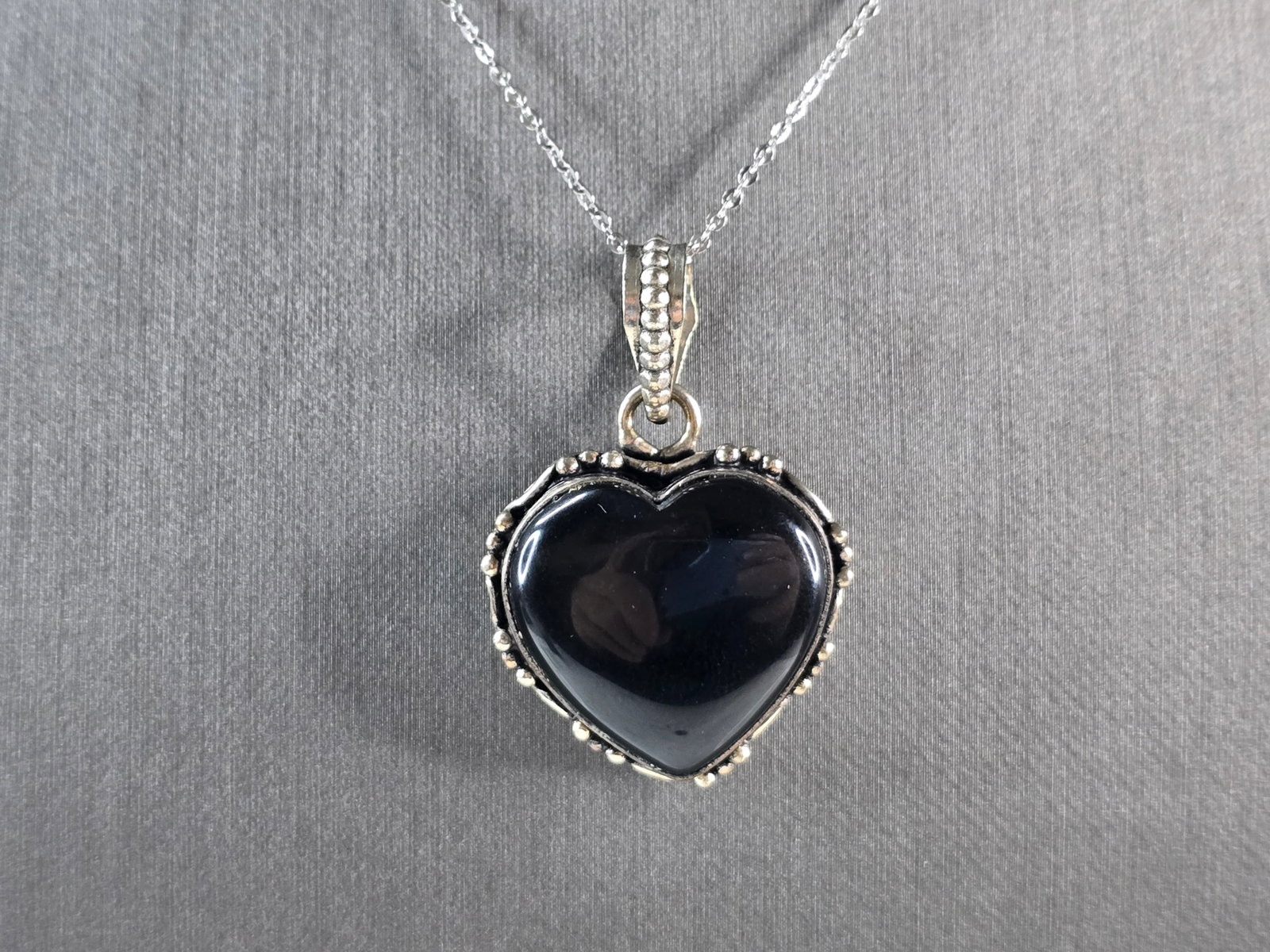 Womens Estate Sterling Silver Onyx Heart Pendant Necklace: A WOMEN'S ESTATE STERLING SILVER ONYX HEART PENDANT WITH NECKLACE. THE NECKLACE MEASURES 18" LONG, AND THE PENDANT MEASURES 1 1/2" LONG BY 1" WIDE. TOGETHER THEY WEIGH 10.9g. NOT SURE IF THE STONE IS 