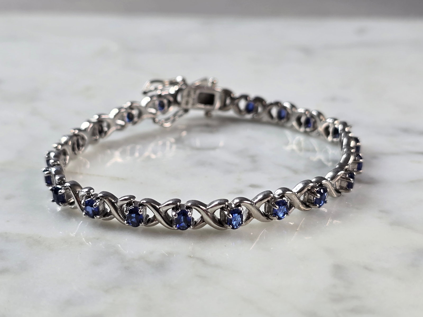 Womens Vintage Estate Sterling Silver Modernist Sapphire Bracelet: A WOMENS VINTAGE ESTATE STERLING SILVER MODERNIST TENNIS BRACELET WITH BLUE SAPPHIRE COLORED STONES. THE BRACELET MEASURES 7 5/8" LONG BY 1/4" WIDE, AND WEIGHS 17.4g. NOT SURE IF THE STONES ARE NATURA