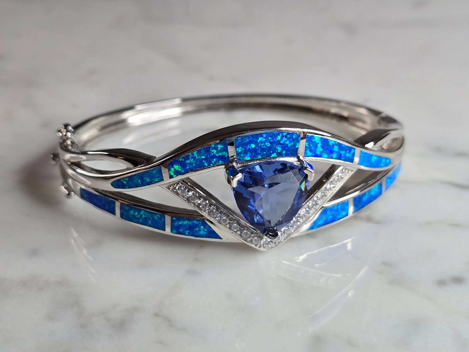 Womens Sterling Silver Modernist Blue Opal Bangle Bracelet: A WOMENS STERLING SILVER MODERNIST BLUE OPAL COLORED BANGLE BRACELET WITH AN AQUA COLORED STONE. THE BRACELET WEIGHS 28.5g AND IS ABOUT 7/8" WIDE. THE CIRCUMFERENCE IS 7". NOT SURE IF THE OPAL IS REAL