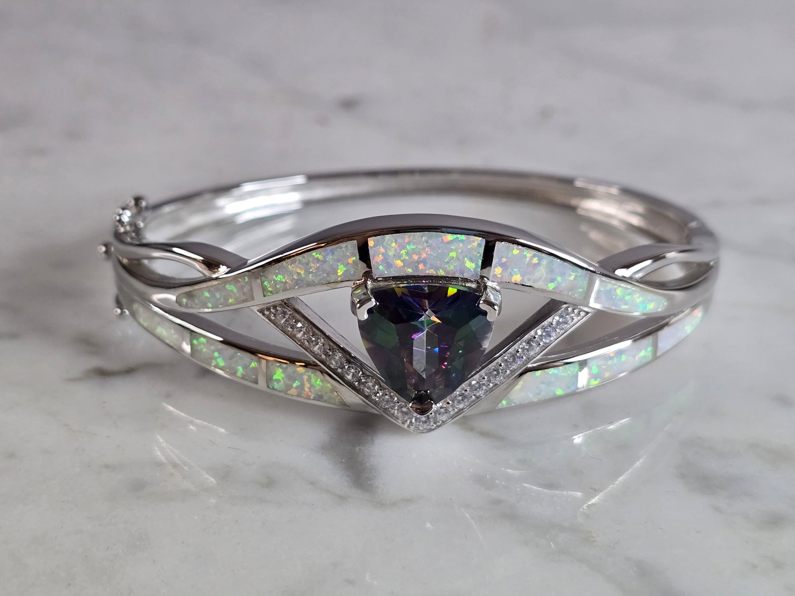 Womens Sterling Silver Modernist Opal Bangle Bracelet: A WOMENS STERLING SILVER MODERNIST OPAL BANGLE BRACELET WITH A MYSTIC TOPAZ COLORED STONE. THE BRACELET WEIGHS 29.6g AND IS ABOUT 7/8" WIDE. THE CIRCUMFERENCE IS 7". NOT SURE IF THE OPAL IS REAL OR MA
