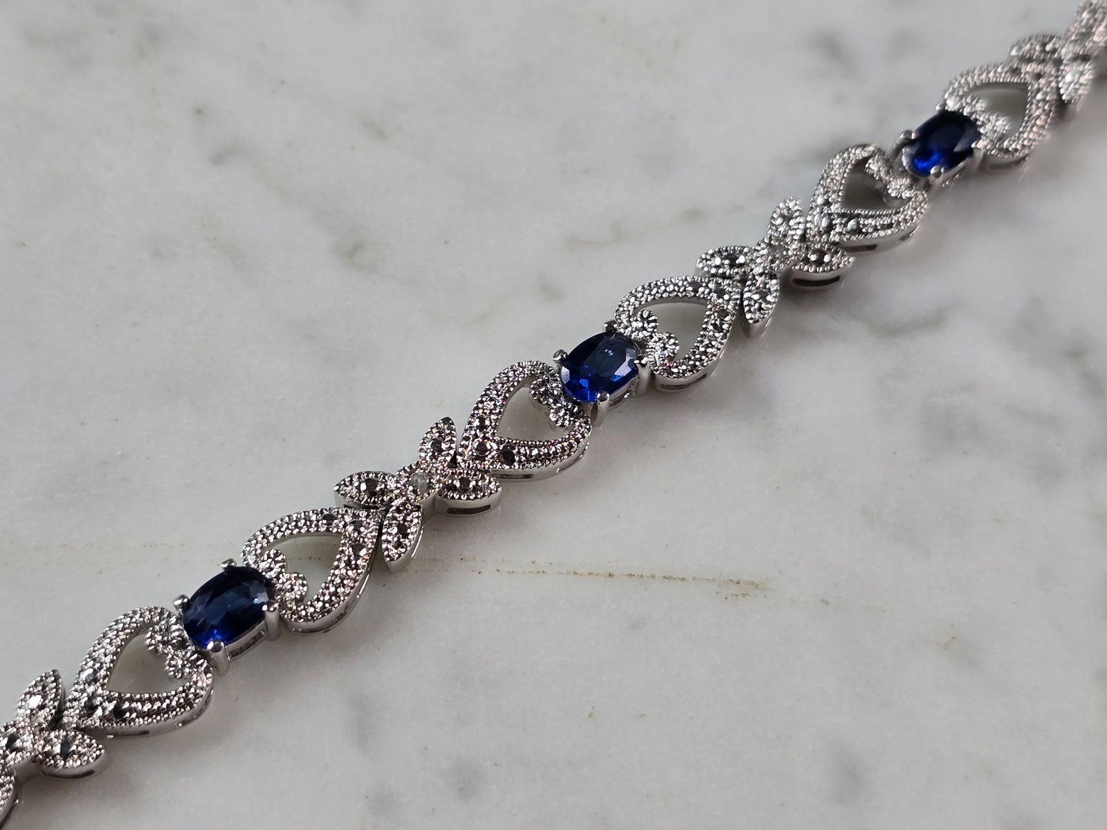 Womens Vintage Estate Sterling Silver Modernist Sapphire Bracelet: A WOMENS VINTAGE ESTATE STERLING SILVER MODERNIST TENNIS BRACELET WITH BLUE SAPPHIRE COLORED STONES. THE BRACELET MEASURES 7 1/4" LONG BY 1/4" WIDE, AND WEIGHS 17.2g. NOT SURE IF THE STONES ARE NATURA