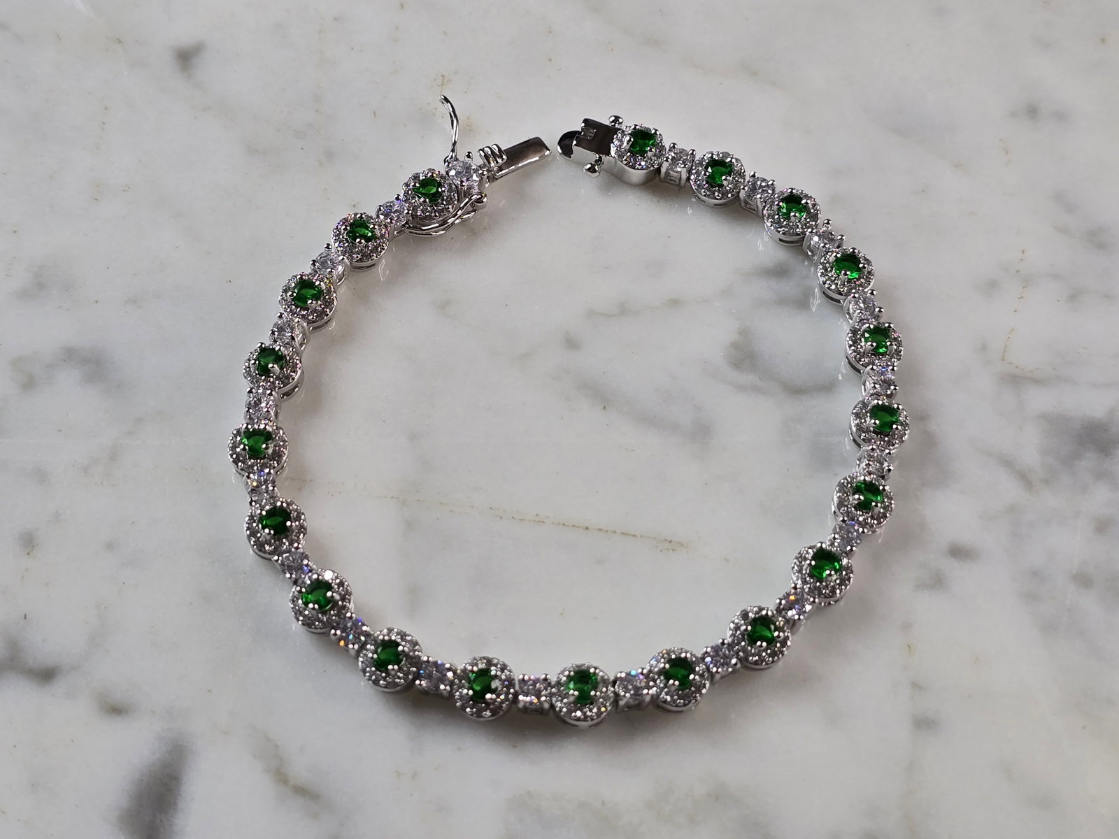Womens Vintage Estate Sterling Silver Modernist Emerald Bracelet: A WOMENS VINTAGE ESTATE STERLING SILVER MODERNIST TENNIS BRACELET WITH EMERALD COLORED STONES. THE BRACELET MEASURES 7 5/8" LONG BY 1/4" WIDE, AND WEIGHS 15.6g. STONES ARE MAN MADE. WOULD MAKE A GREAT