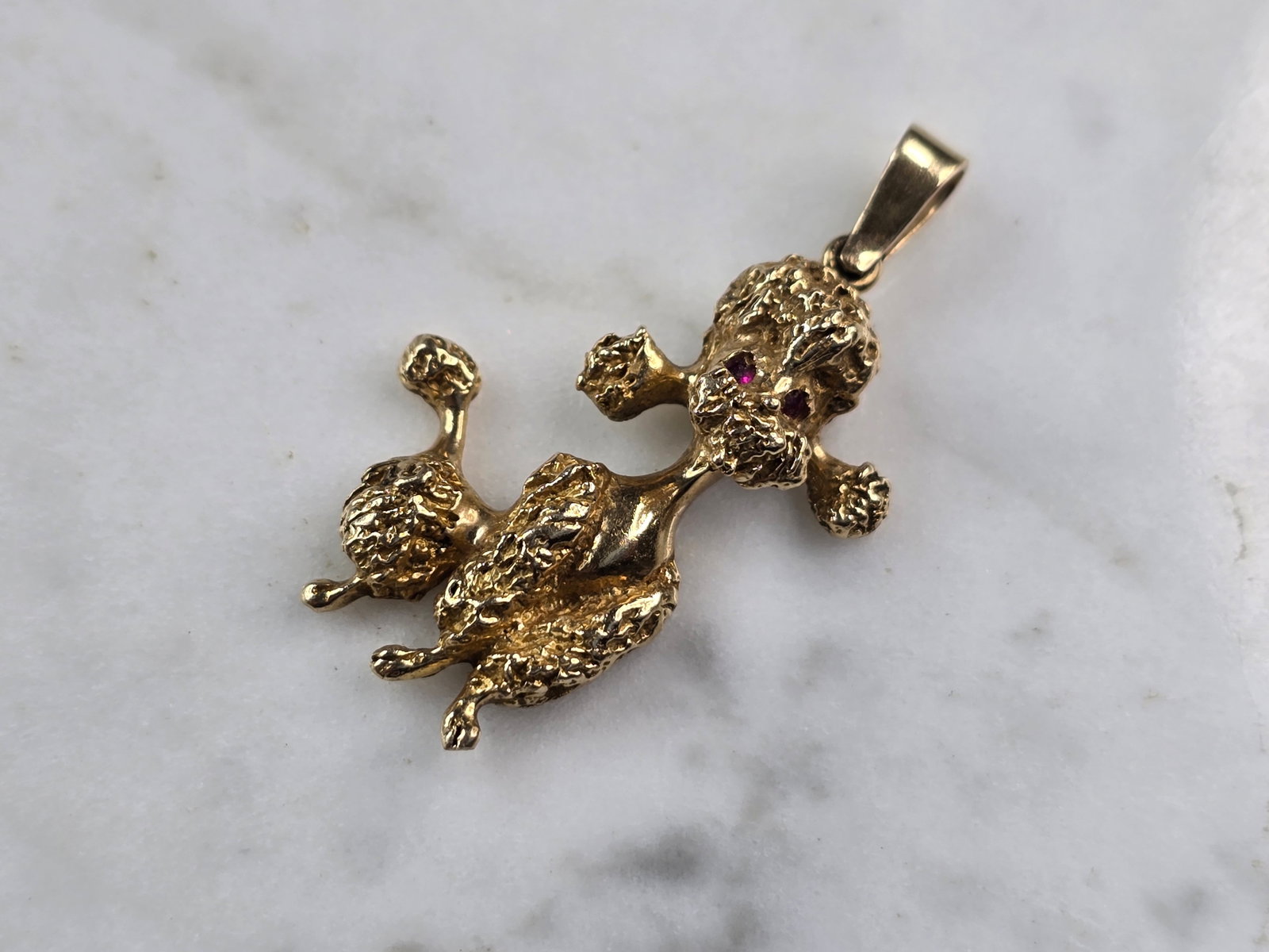 Womens Vintage Estate 14k Gold Poodle Dog Pendant: A WOMENS VINTAGE 14K YELLOW GOLD POODLE PENDANT WITH GARNET EYES. THE TOTAL WEIGHT IS 6.7g. THE PENDANT MEASURES 1 3/8" LONG BY 3/4" WIDE. PENDANT IS NOT MARKED BUT IT HAS BEEN TESTED AND IS GUARANTEE