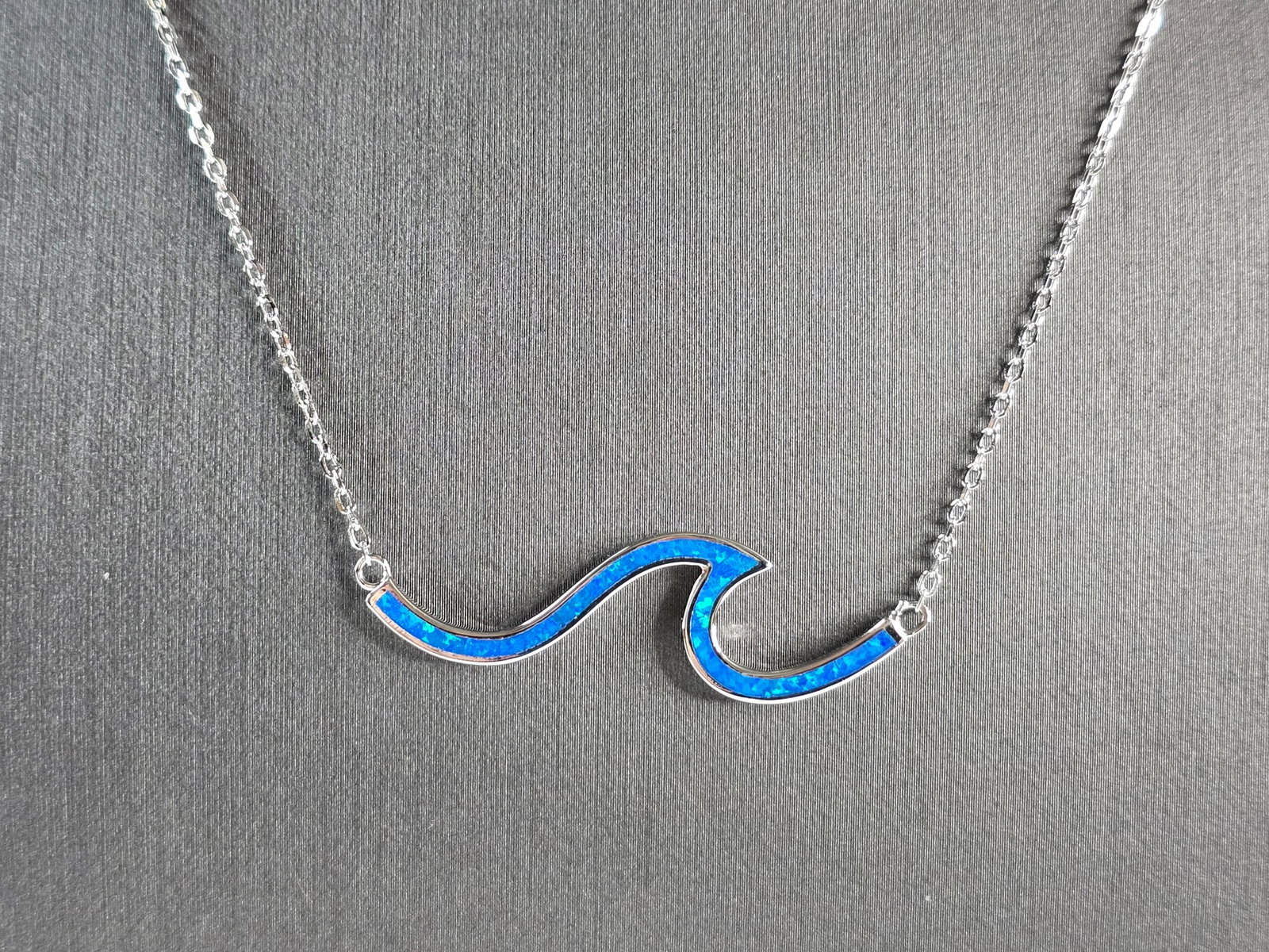 Womens Sterling Silver Blue Opal Tsunami Wave Pendant Necklace: A WOMENS STERLING SILVER BLUE OPAL TSUNAMI WAVE PENDANT. THE PENDANT WITH NECKLACE WEIGHS 4.0g. THE PENDANT MEASURES 1 5/8" LONG BY 1/2" WIDE, AND THE NECKLACE MEASURES 18" LONG. NOT SURE IF STONES AR