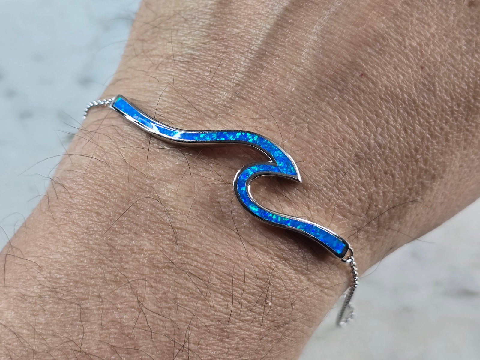 Womens Sterling Silver Blue Opal Tsunami Wave Adjustable Bracelet: A WOMENS STERLING SILVER BLUE OPAL TSUNAMI WAVE ADJUSTABLE BRACELET. THE BRACELET WEIGHS 8.4g. THE BRACELET MEASURES 9 1/2" AT ITS MAX. THE BAR MEASURES 2 1/8" LONG BY 1/2" WIDE. NOT SURE IF STONES AR