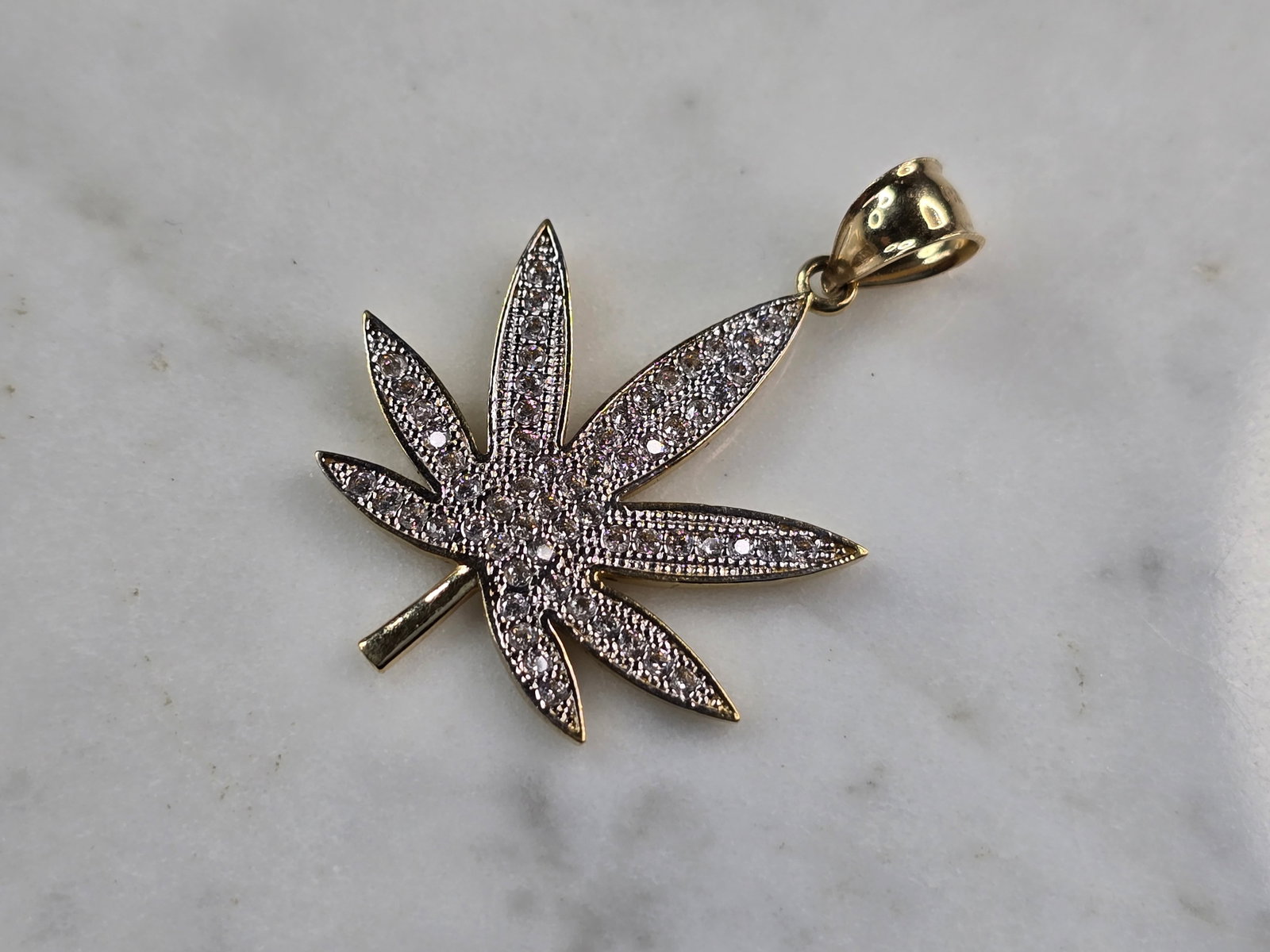 Blinged Out 14K Yellow Gold Marijuana Pot Leaf Pendant: FOR SALE IS THIS BLINGED OUT 14K YELLOW GOLD MARIJUANA LEAF PENDANT ACCENTED WITH CZ CRYSTALS. THE PENDANT WEIGHS 3.7g, AND MEASURES 1 3/8" BY 7/8". PENDANT IS STAMPED "14KM". NOT SURE WHAT THE "M" ME