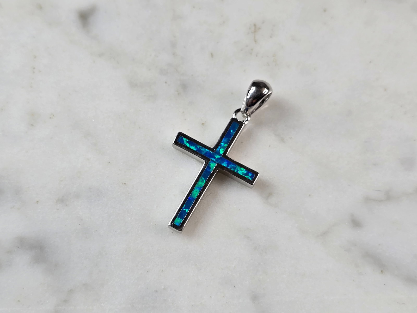 Womens Sterling Silver Blue Opal Religious Cross Pendant: A WOMENS STERLING SILVER BLUE OPAL RELIGIOUS CROSS PENDANT. NOT SURE IF STONES ARE REAL OR MAN MADE. THE PENDANT WEIGHS 1.7g AND MEASURES 1" LONG BY 5/8" WIDE. MAKES A GREAT GIFT FOR THAT SOMEONE SPEC