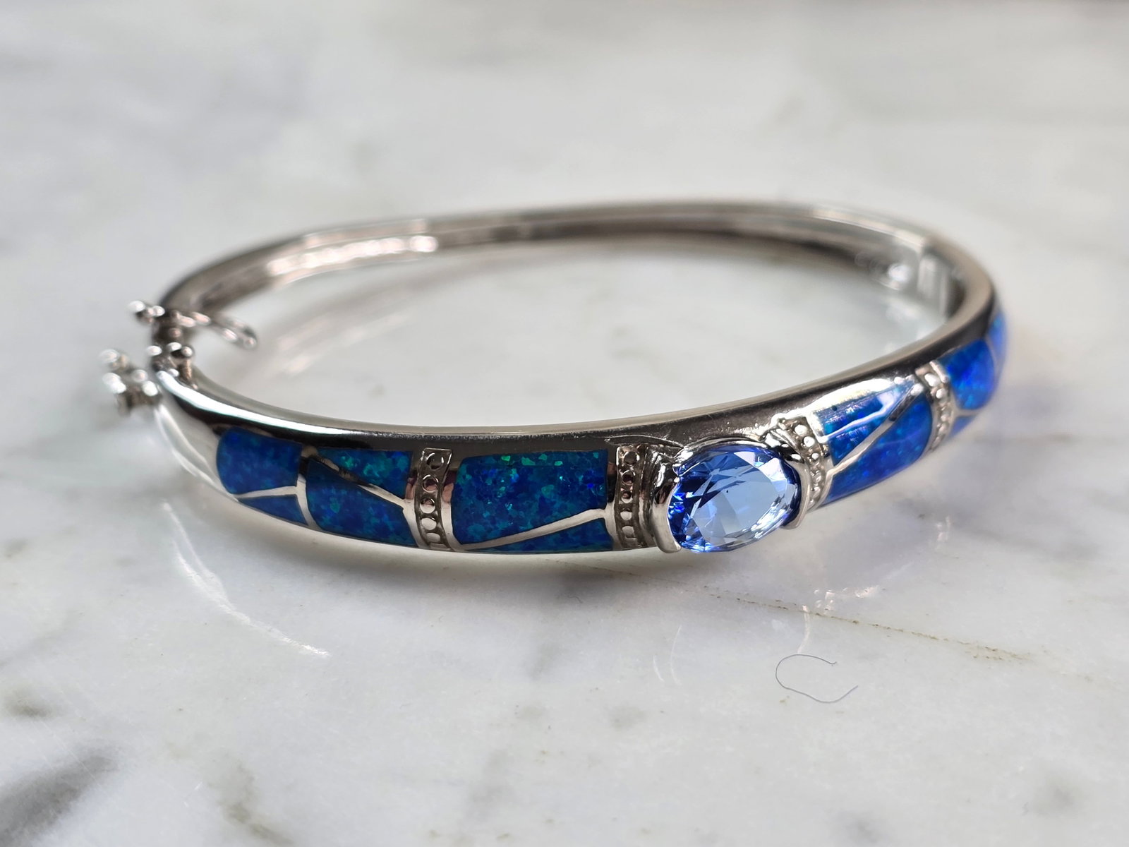 Womens Sterling Silver Modernist Blue Opal Bangle Bracelet: A WOMENS STERLING SILVER MODERNIST BLUE OPAL BANGLE BRACELET WITH A TANZANITE COLORED STONE. THE BRACELET WEIGHS 19.1g AND IS ABOUT 3/8" WIDE. THE CIRCUMFERENCE IS 7". NOT SURE IF THE OPAL IS REAL OR 