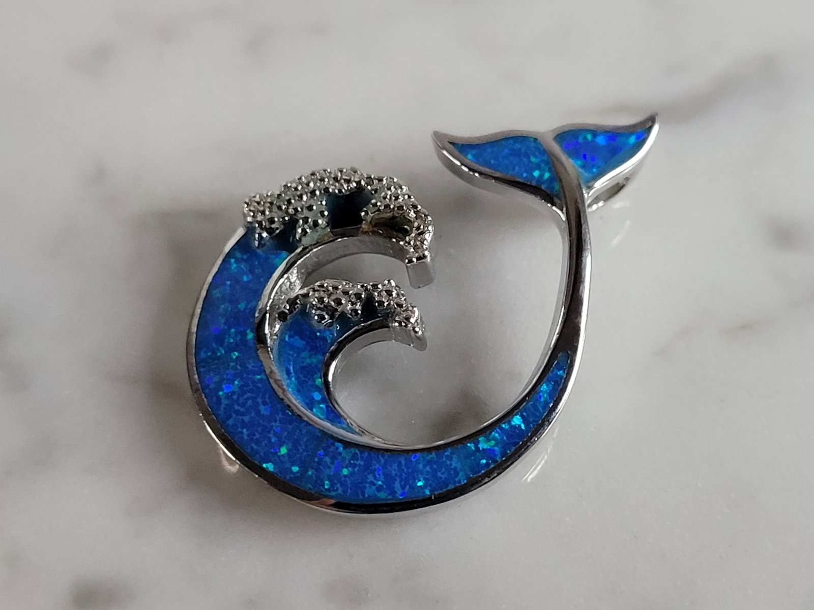 Womens Sterling Silver Blue Opal Modernist Whale Pendant: A WOMENS STERLING SILVER BLUE OPAL MODERNIST WHALE PENDANT. NOT SURE IF STONES ARE REAL OR MAN MADE. THE PENDANT WEIGHS 3.6g AND MEASURES 1 1/8" LONG BY 3/4" WIDE. MAKES A GREAT GIFT FOR THAT SOMEONE 