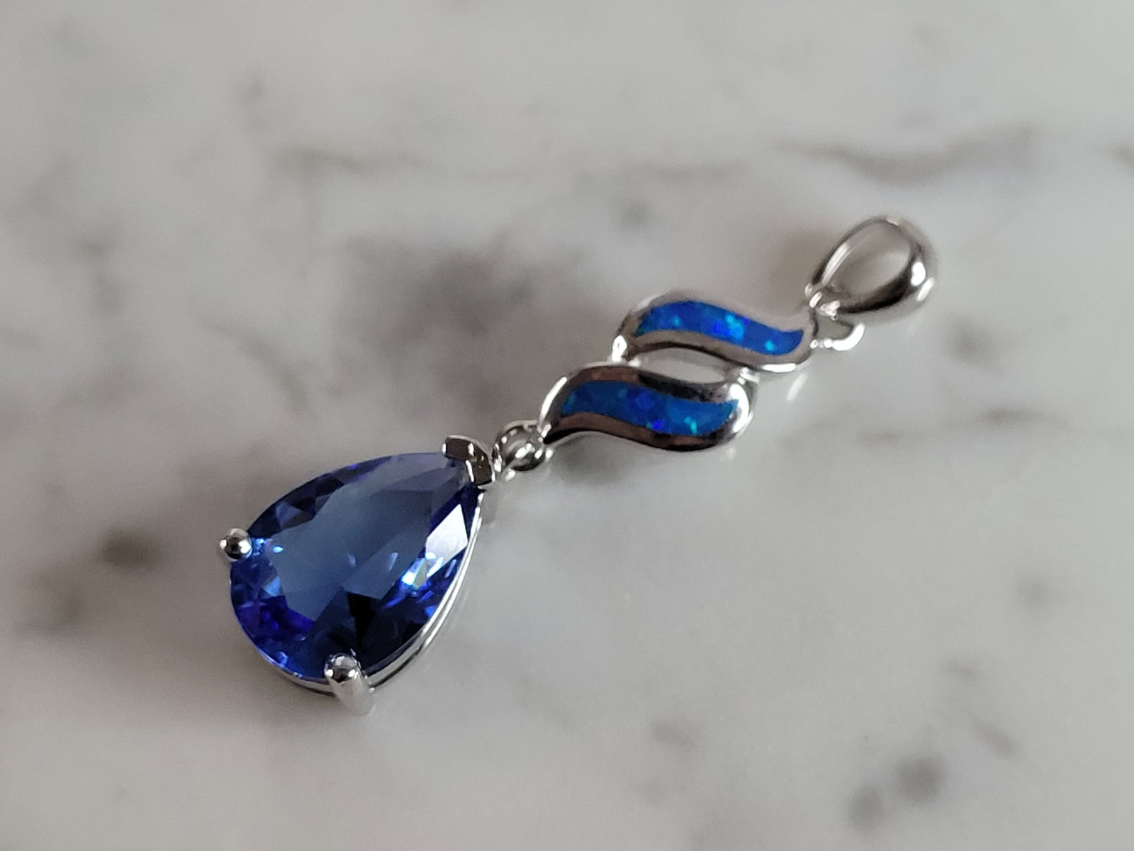 Womens Sterling Silver Blue Opal Modernist Pendant: A WOMENS STERLING SILVER BLUE OPAL MODERNIST PENDANT WITH A TANZANITE COLORED STONE. NOT SURE IF STONES ARE REAL OR MAN MADE. THE PENDANT WEIGHS 3.7g AND MEASURES 1 1/2" LONG BY 3/8" WIDE. MAKES A GRE