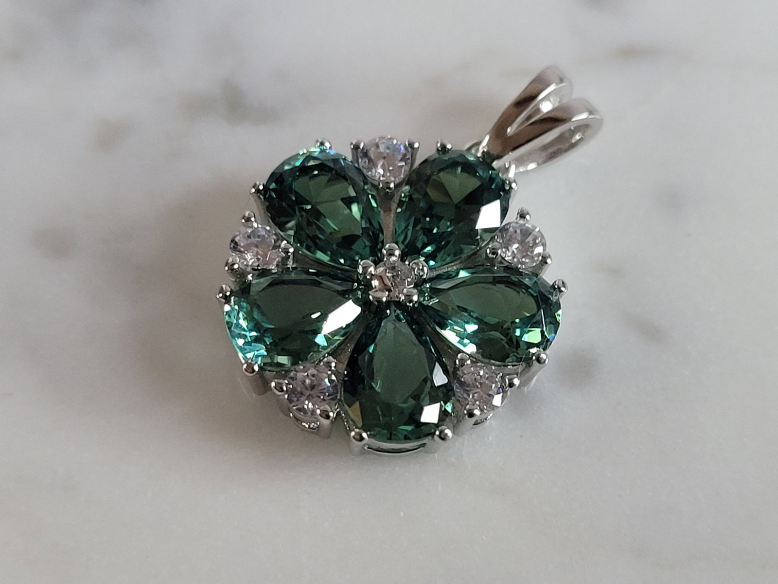 Womens Estate Sterling Silver Modernist CZ Floral Pendant: A WOMENS ESTATE STERLING SILVER MODERNIST CZ FLORAL PENDANT WITH AN EMERALD COLORED STONE. PENDANT WEIGHS 2.9g AND MEASURES 7/8" LONG BY 5/8" WIDE. MAKES A GREAT GIFT FOR THAT SOMEONE SPECIAL. ANY QUE