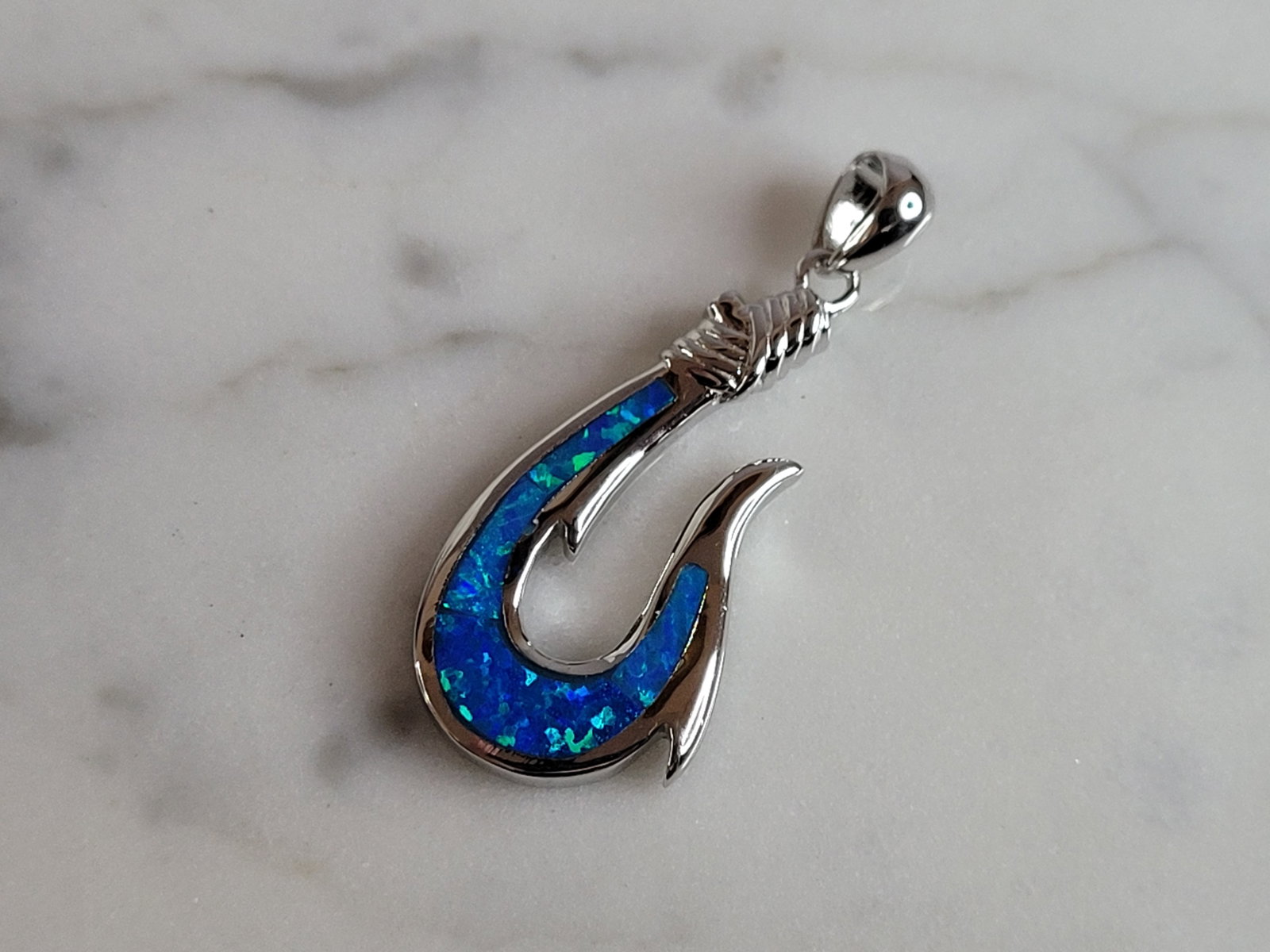 Womens Sterling Silver Blue Opal Hawaiian Fish Hook Pendant: A WOMENS STERLING SILVER BLUE OPAL HAWAIIAN FISH HOOK PENDANT. NOT SURE IF STONES ARE REAL OR MAN MADE. THE PENDANT WEIGHS 3.8g AND MEASURES 1 1/4" LONG BY 1/2" WIDE. MAKES A GREAT GIFT FOR THAT SOMEO