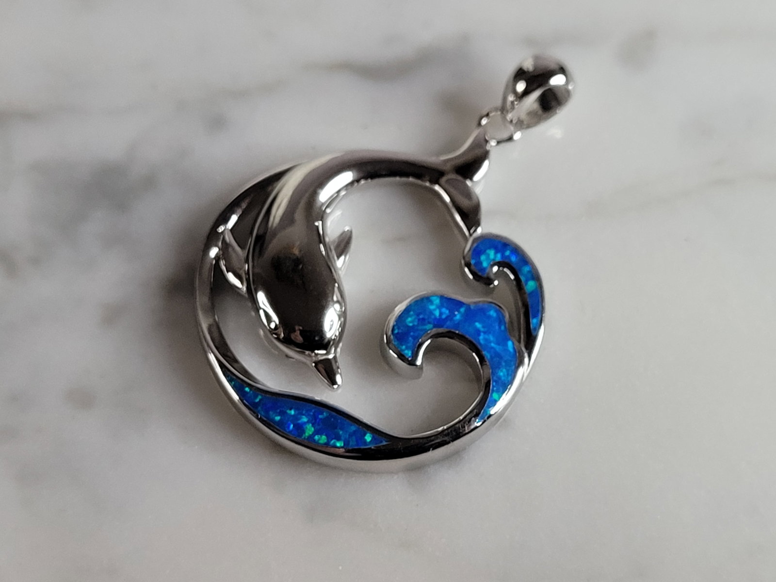 Womens Sterling Silver Blue Opal Dolphin Pendant: A WOMENS STERLING SILVER BLUE OPAL DOLPHIN PENDANT. NOT SURE IF STONES ARE REAL OR MAN MADE. THE PENDANT WEIGHS 7.1g AND MEASURES 1 1/2" LONG BY 1" WIDE. MAKES A GREAT GIFT FOR THAT SOMEONE SPECIAL. A