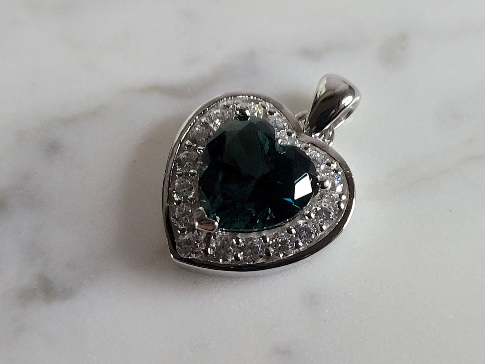 Womens Sterling Silver Modernist CZ Heart Pendant: A WOMENS STERLING SILVER MODERNIST CZ HEART PENDANT WITH AN EMERALD COLORED STONE. PENDANT WEIGHS 4.9g AND MEASURES 7/8" LONG BY 5/8" WIDE. MAKES A GREAT GIFT FOR THAT SOMEONE SPECIAL. ANY QUESTIONS, 
