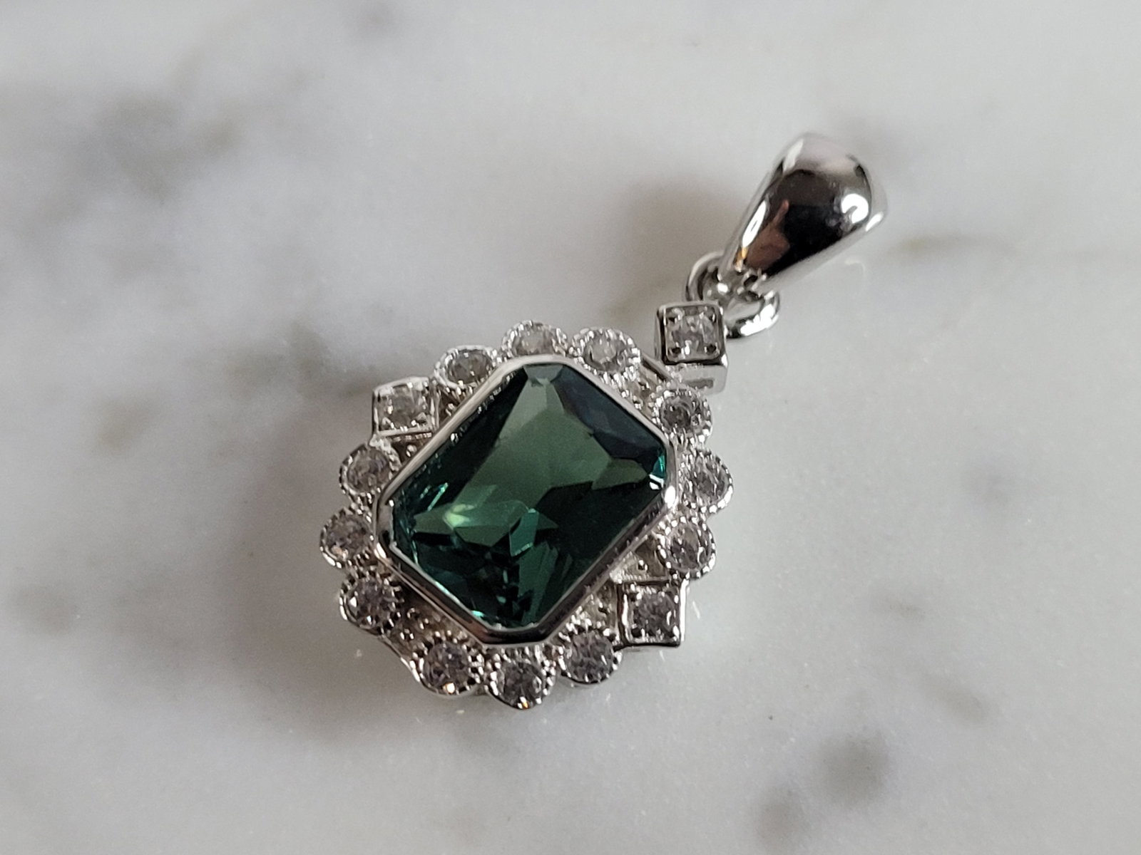 Womens Sterling Silver Modernist CZ Pendant: A WOMENS STERLING SILVER MODERNIST CZ PENDANT WITH AN EMERALD COLORED STONE. PENDANT WEIGHS 2.1g AND MEASURES 7/8" LONG BY 1/2" WIDE. MAKES A GREAT GIFT FOR THAT SOMEONE SPECIAL. ANY QUESTIONS, PLEASE