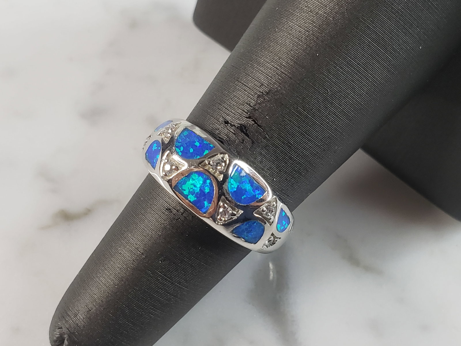 Womens Estate Sterling Silver Modernist Blue Opal & CZ Ring: A WOMENS ESTATE STERLING SILVER MODERNIST BLUE OPAL COLORED RING. THE RING IS A SIZE 6.0 AND WEIGHS 4.6g. WIDTH OF RING MEASURES 3/8". NOT SURE IF STONE IS NATURAL OR MAN MADE. THE RING MAKES A BEAUTI