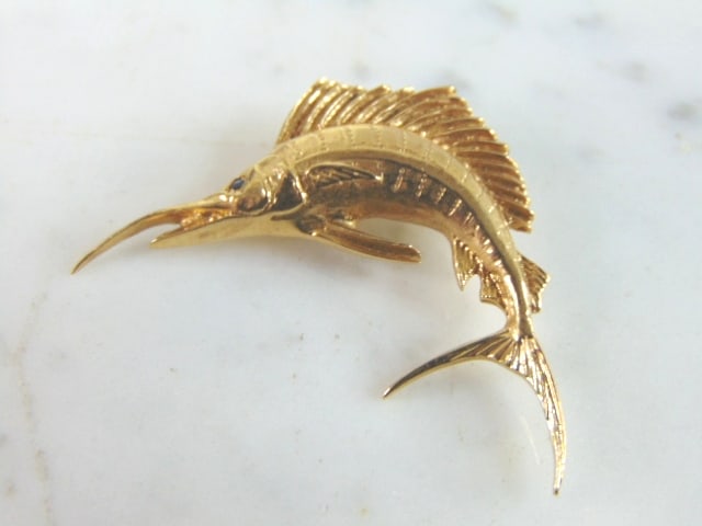 Vintage Estate 14K Yellow Gold Sword Fish Pendant: A VINTAGE ESTATE 14K GOLD SWORD FISH PENDANT WITH A SAPPHIRE EYE. THE PENDANT MEASURES 1 3/4" BY 1", AND WEIGHS 6.2g. NO MARK, BUT IT HAS BEEN TESTED AND IS GUARANTEED TO BE AS DESCRIBED. MAKES A GREA