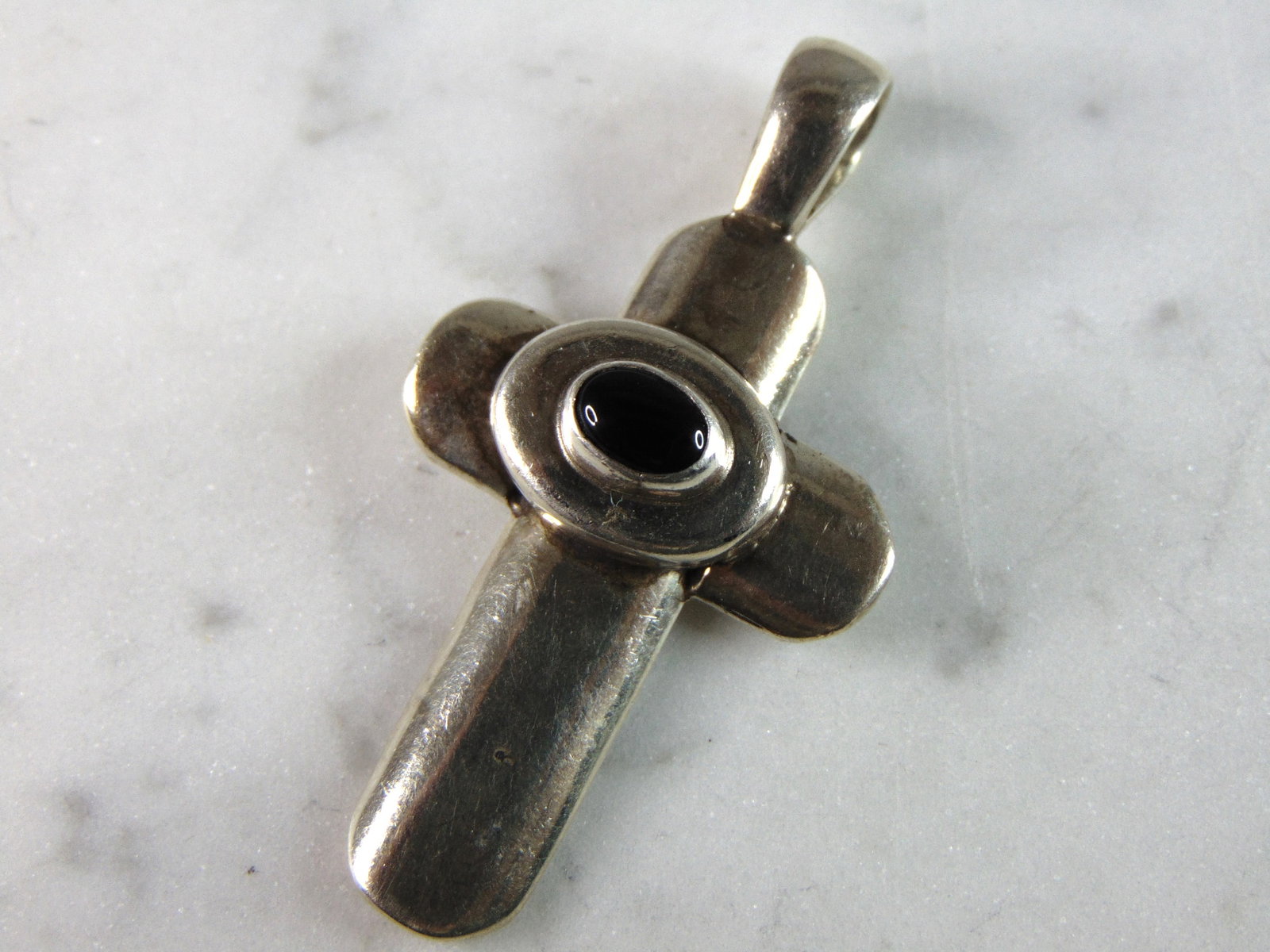 Womens Vintage Estate Sterling Silver Onyx Cross Pendant: A WOMENS VINTAGE ESTATE STERLING SILVER ONYX CROSS PENDANT. THE PENDANT WEIGHS 12.1g. NOT SURE IF STONE IS NATURAL OR MAN MADE. THE PENDANT MEASURES 2" LONG BY 1" WIDE. THIS WOULD MAKE A NICE GIFT FOR