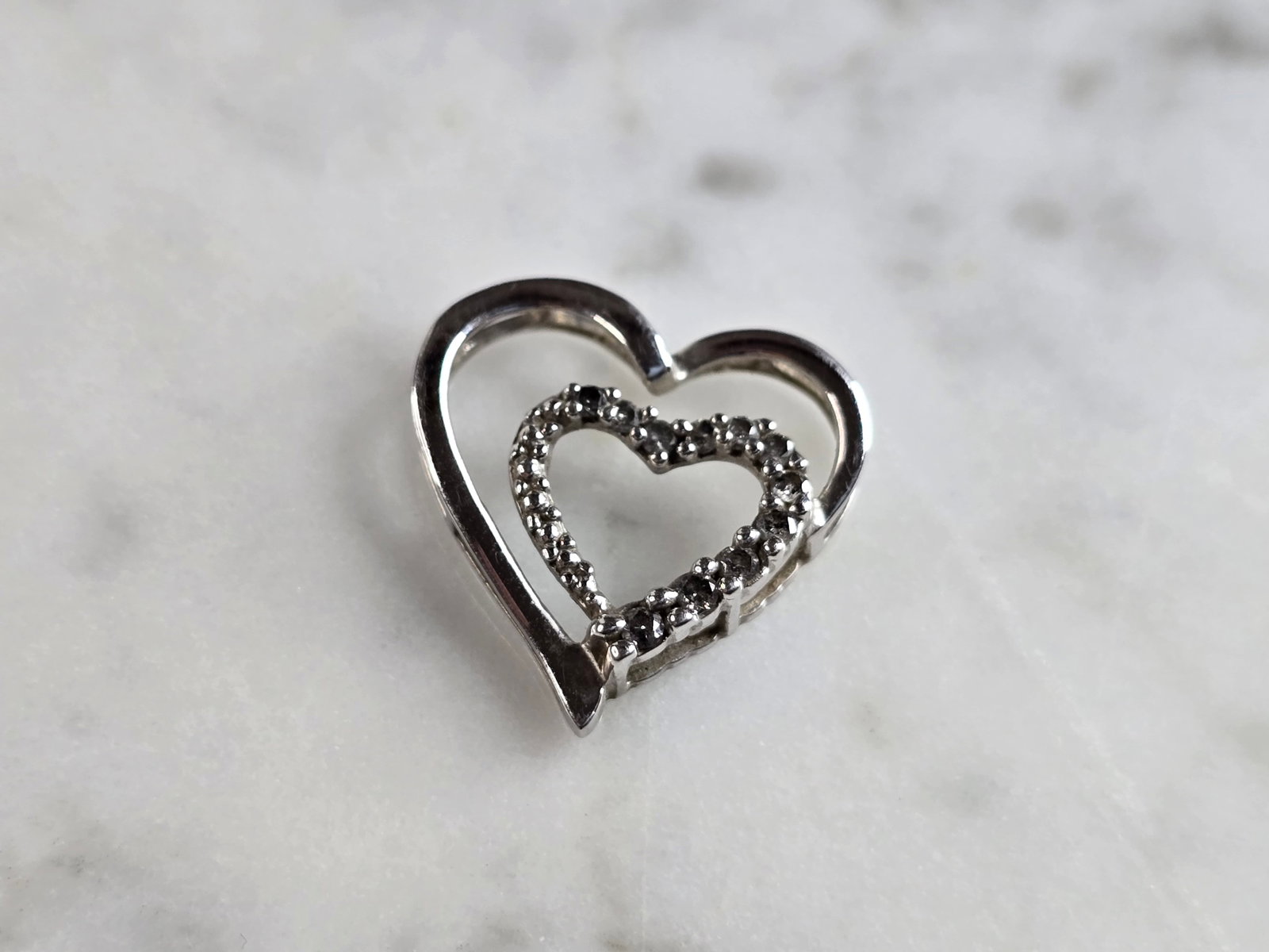 Womens Vintage Estate 10K White Gold Heart Diamond Pendant: A WOMENS VINTAGE ESTATE 10K WHITE GOLD DIAMOND HEART PENDANT. THE PENDANT WEIGHS 1.1g, AND MEASURES 5/8" LONG BY 5/8" WIDE. THERE ARE ABOUT .11cts OF DIAMONDS. PENDANT IS MARKED ON THE BACK. MAKES A G