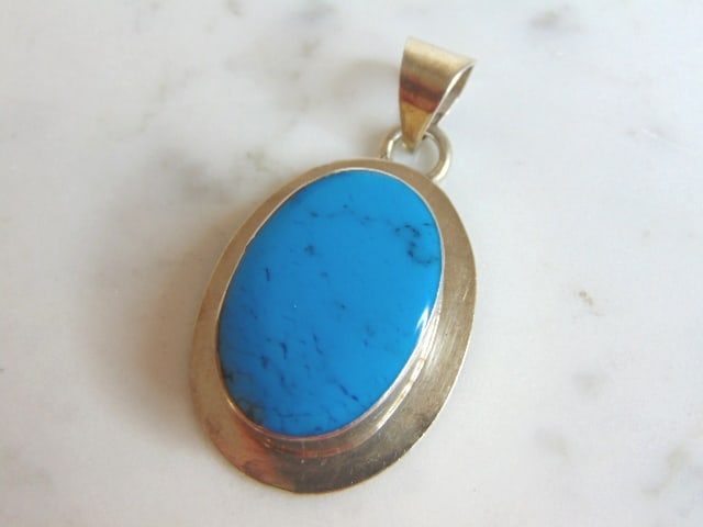 Womens Vintage Estate Sterling Silver Turquoise Pendant: A WOMENS VINTAGE ESTATE STERLING SILVER TURQUOISE COLORED PENDANT. NOT SURE IF STONE IS REAL OR MAN MADE. PENDANT WEIGHS 12.3g AND PENDANT MEASURES 1 3/4" LONG BY 1" WIDE. MAKES A GREAT GIFT FOR THAT 